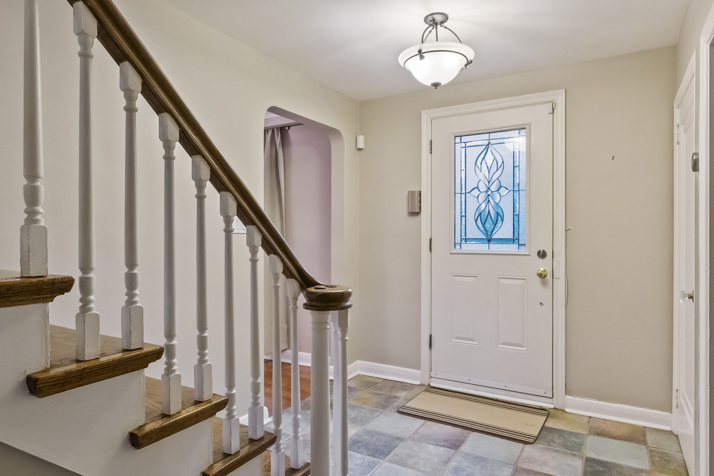 Bright entryway with a staircase, door, and colorful tiled floor