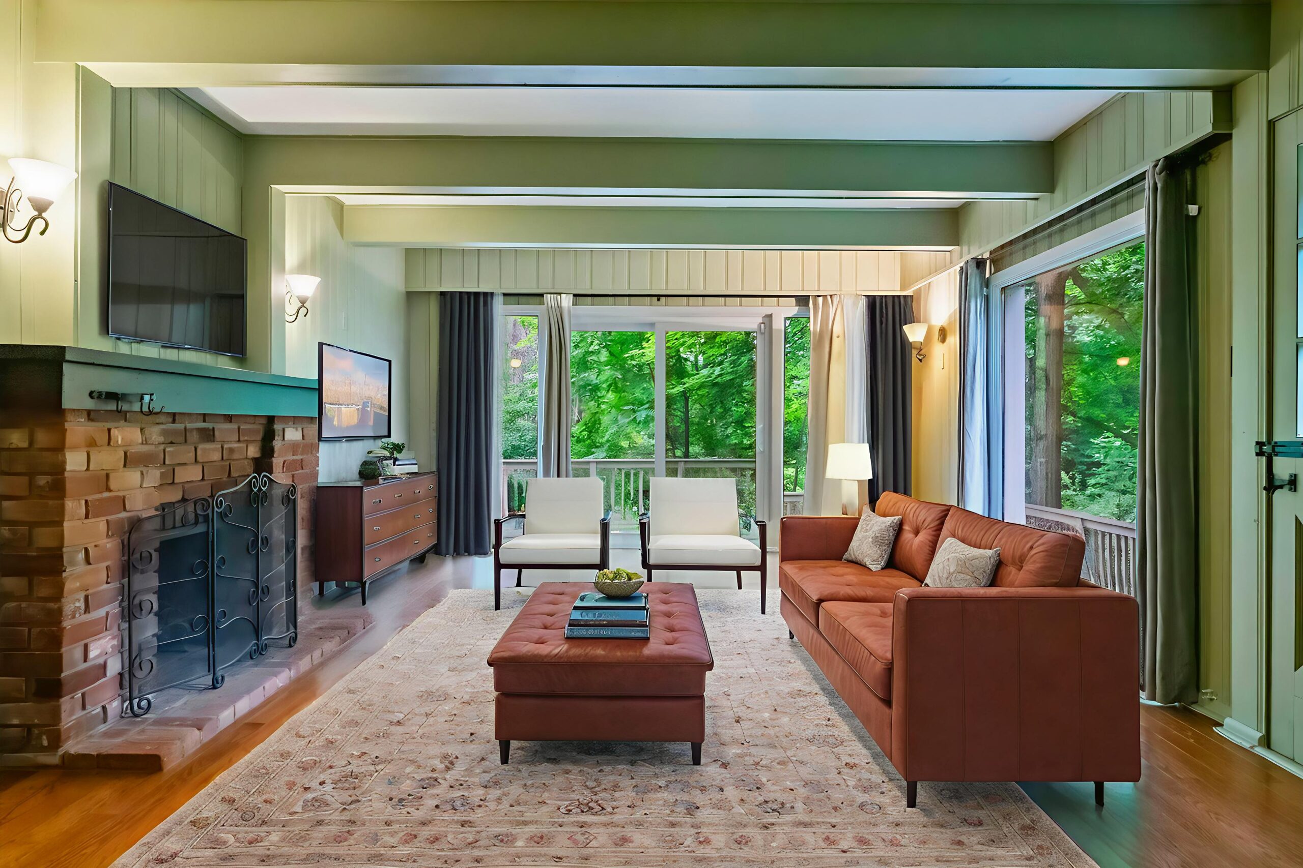 Cozy living room with brown sofa, fireplace, and large windows overlooking greenery