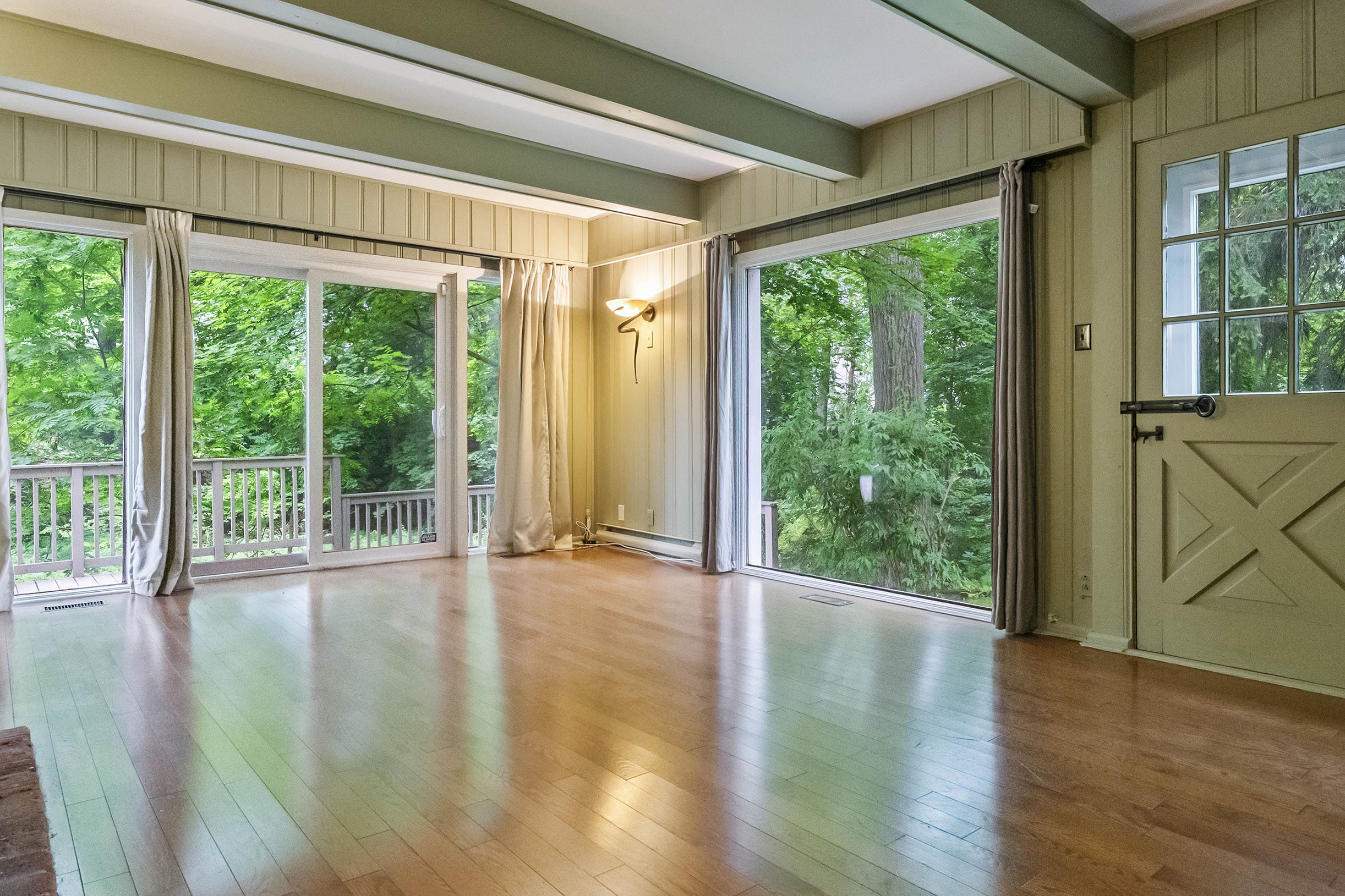 Spacious room with hardwood floors and large windows overlooking greenery