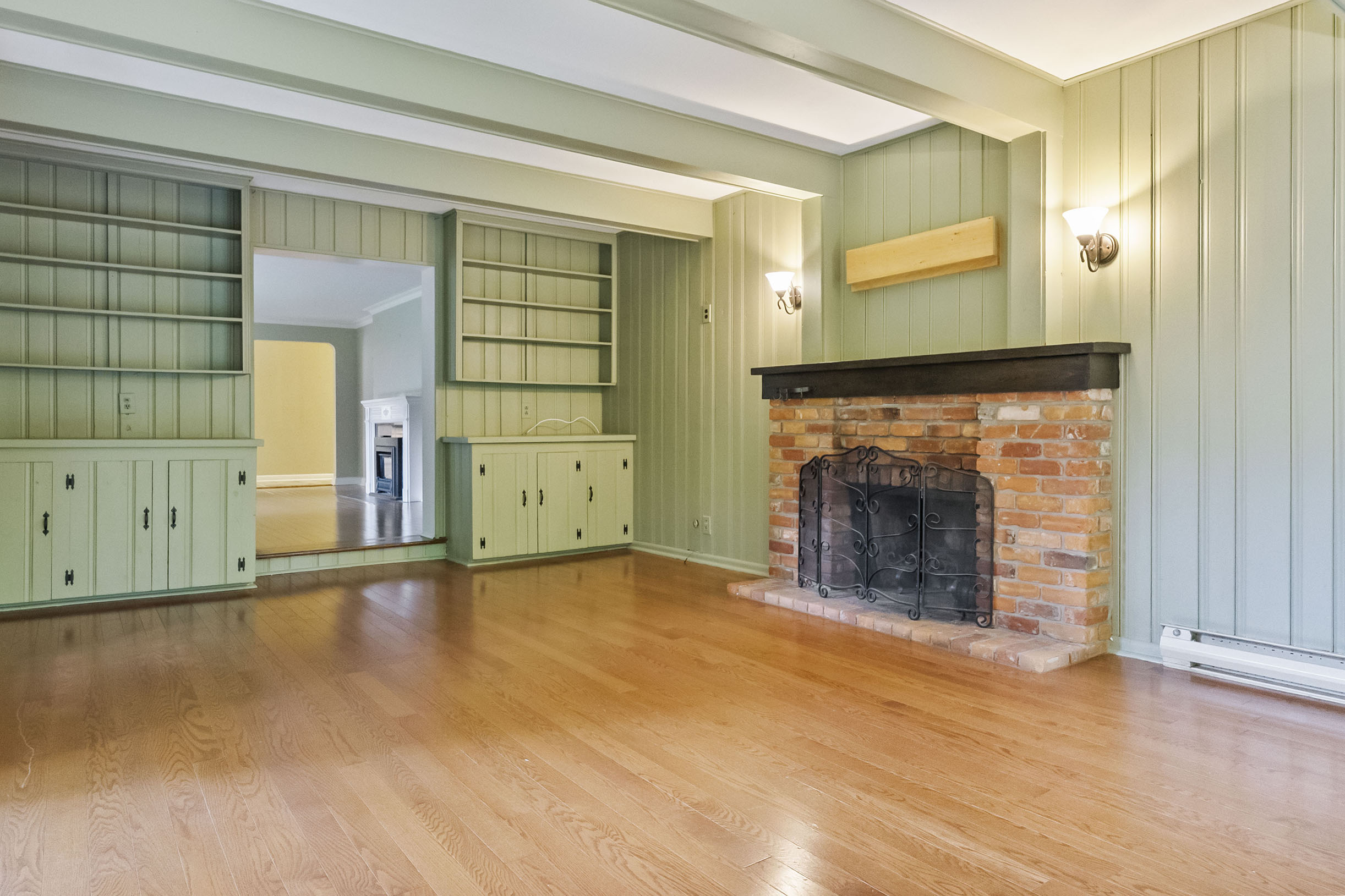 Spacious living room with green walls and a brick fireplace