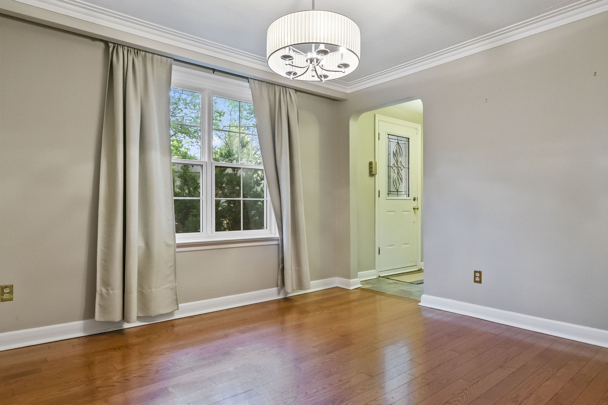 Empty room with hardwood floor, window, and modern chandelier