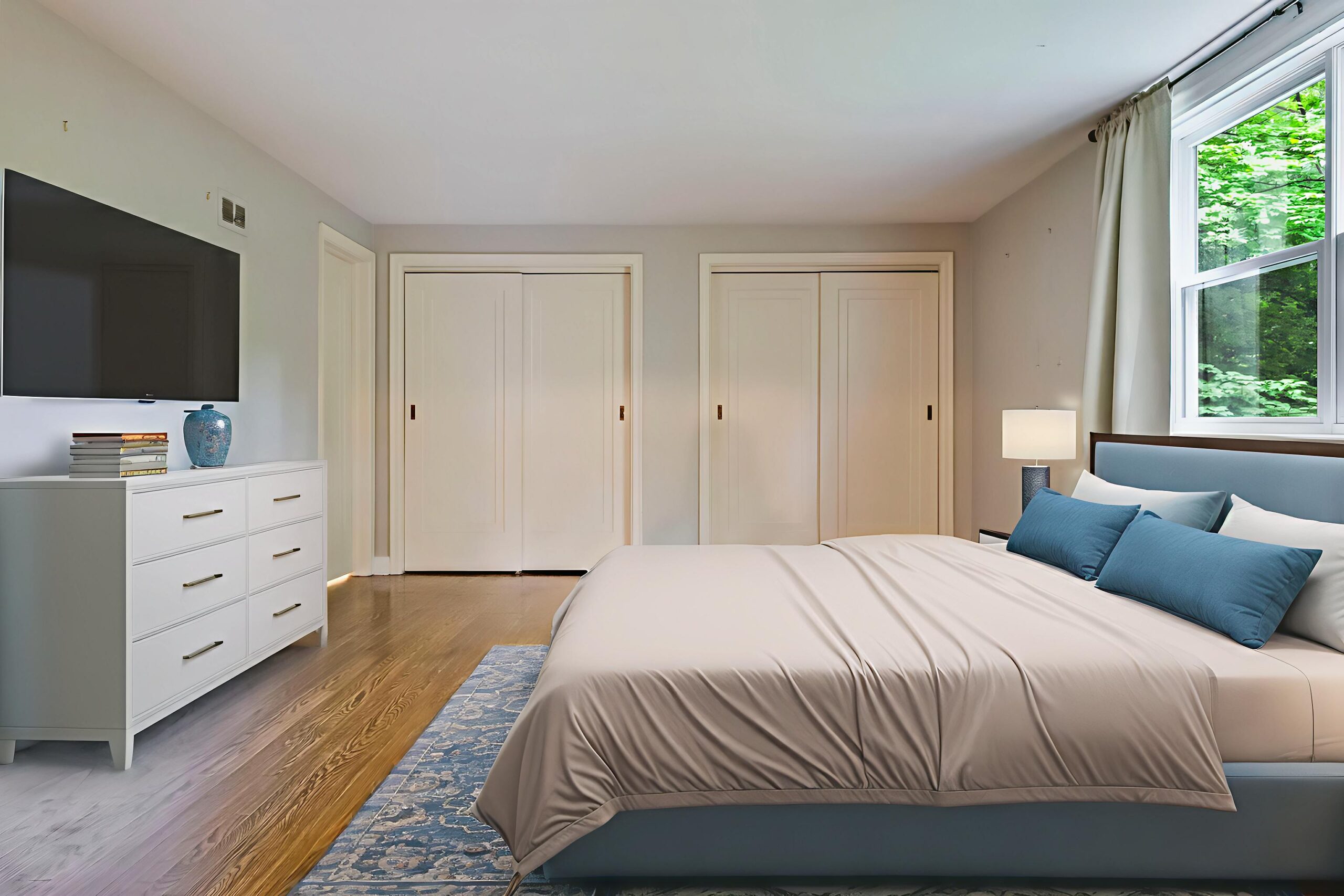 Modern bedroom with a large bed, dresser, and natural light from a window