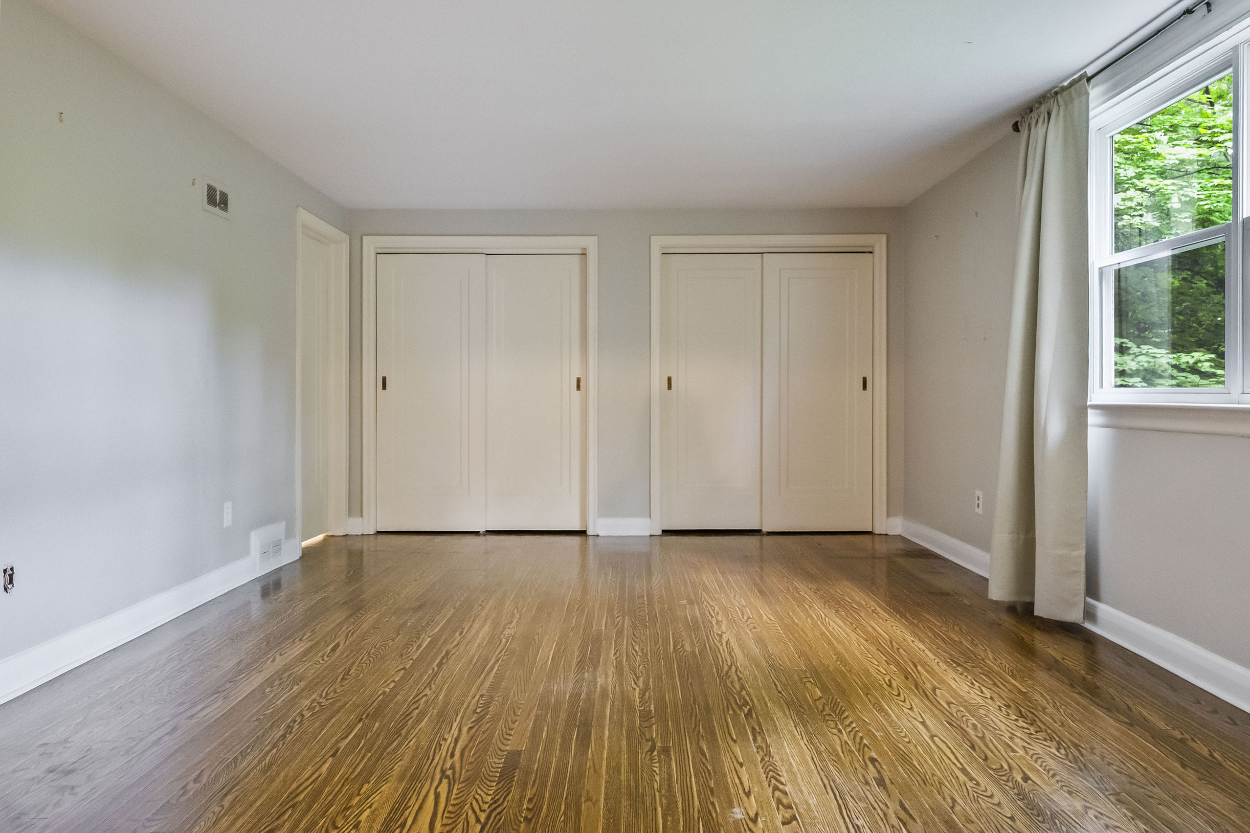 Empty room with hardwood floor and two closet doors