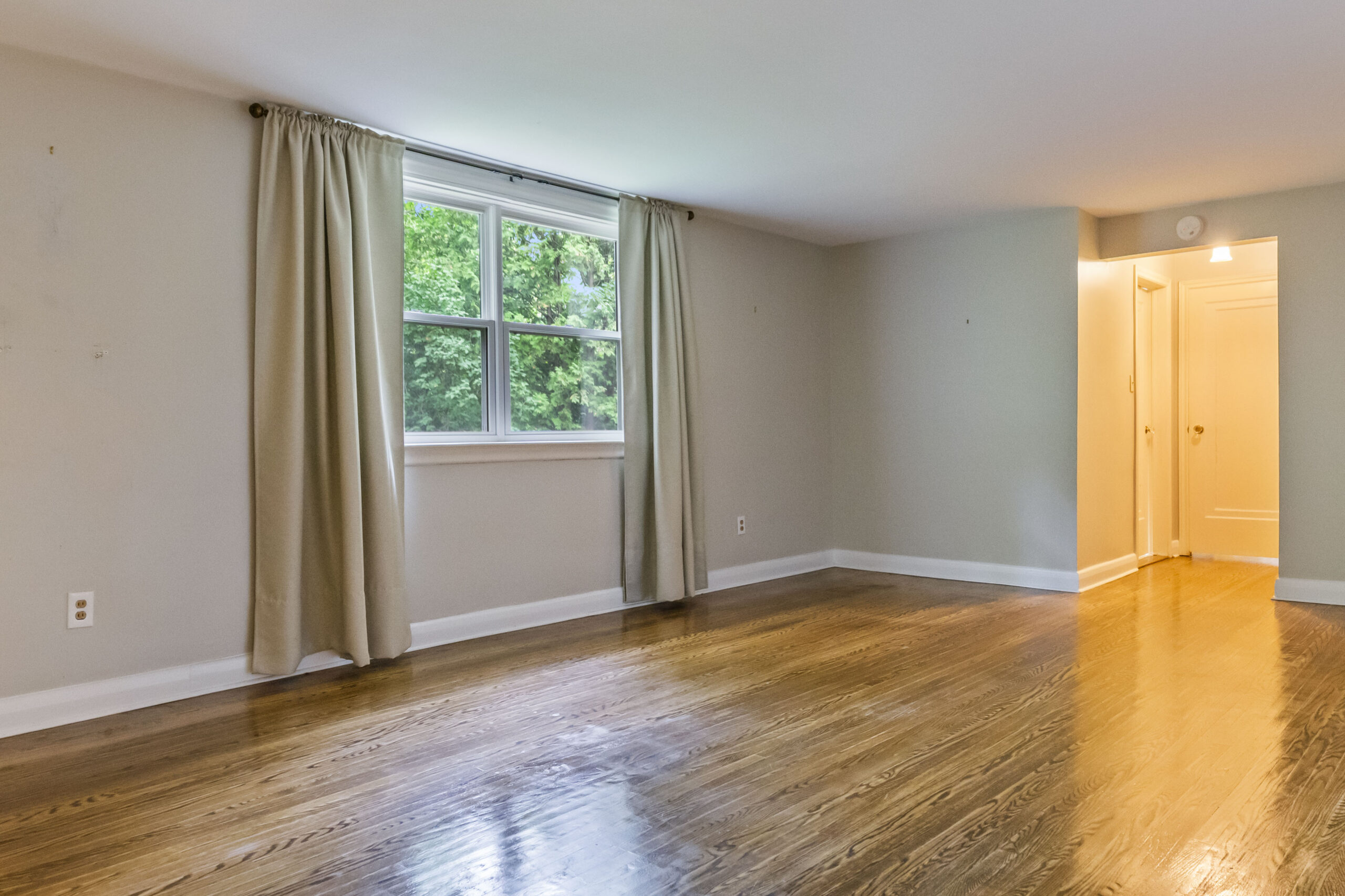 Spacious room with hardwood floors and natural light from a window