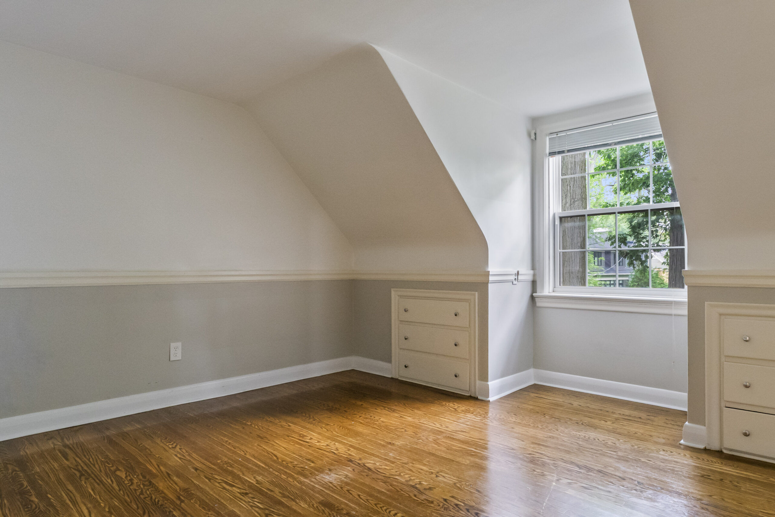 Bright attic room with sloped ceiling and wooden floor