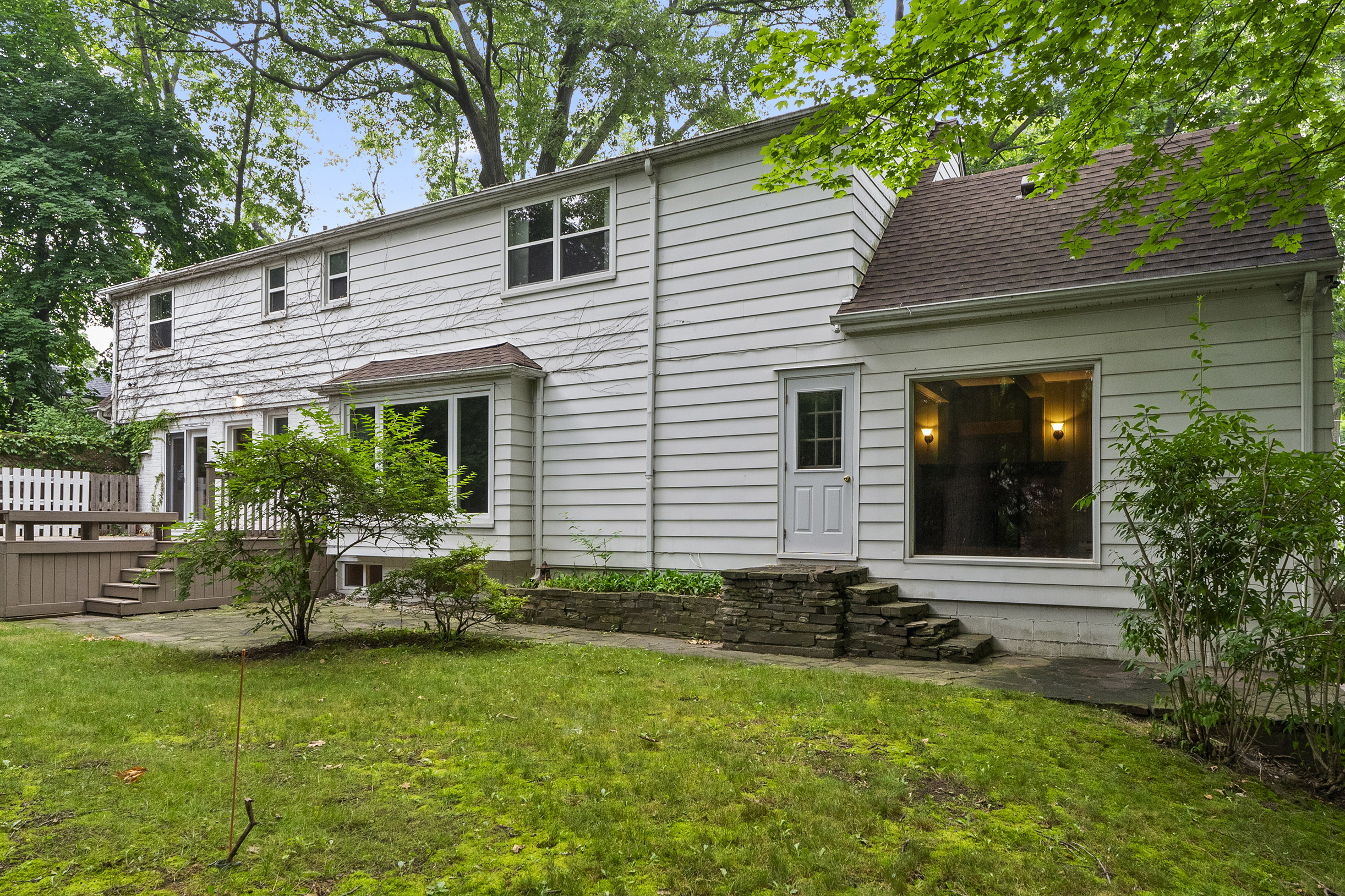 Two-story white house with green lawn and trees in the background