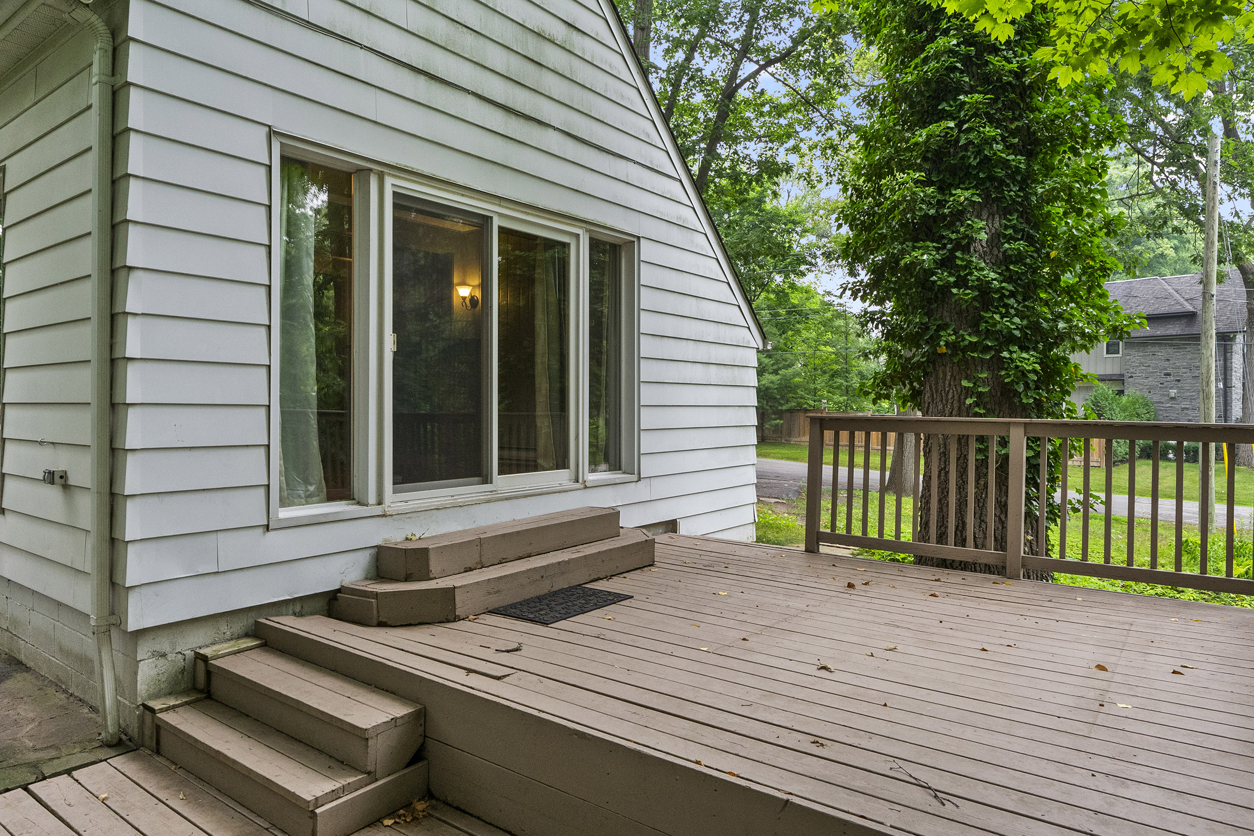 Back porch with steps leading to a grassy area and trees