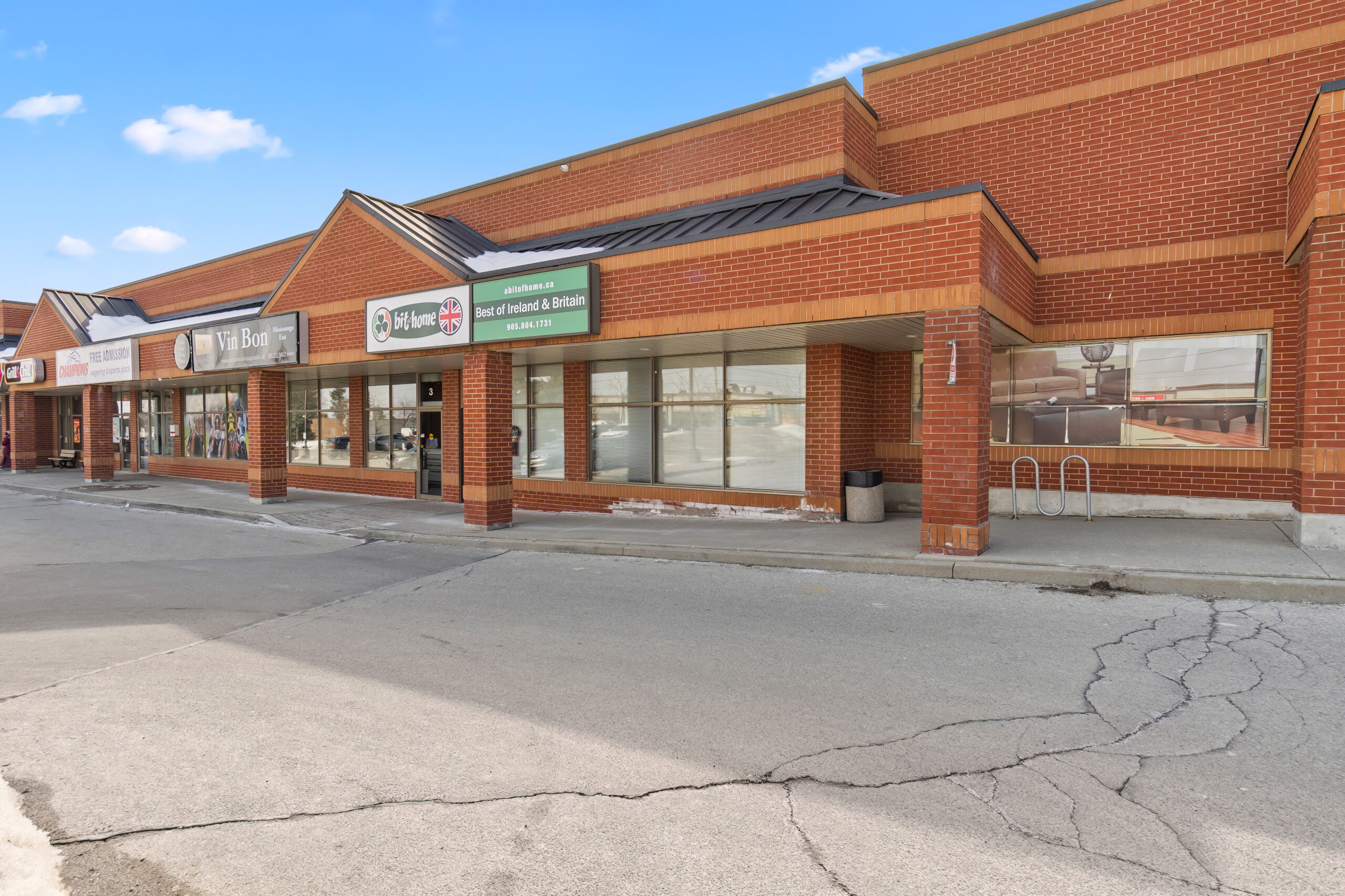 Brick storefronts with large windows and blue sky above