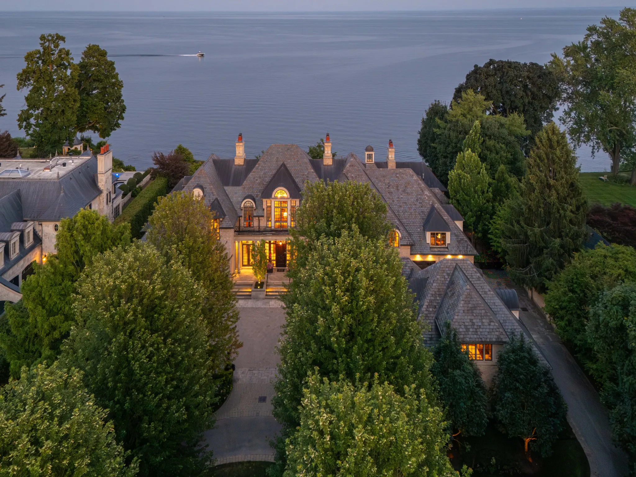 exterior house with large green trees and lake in the background