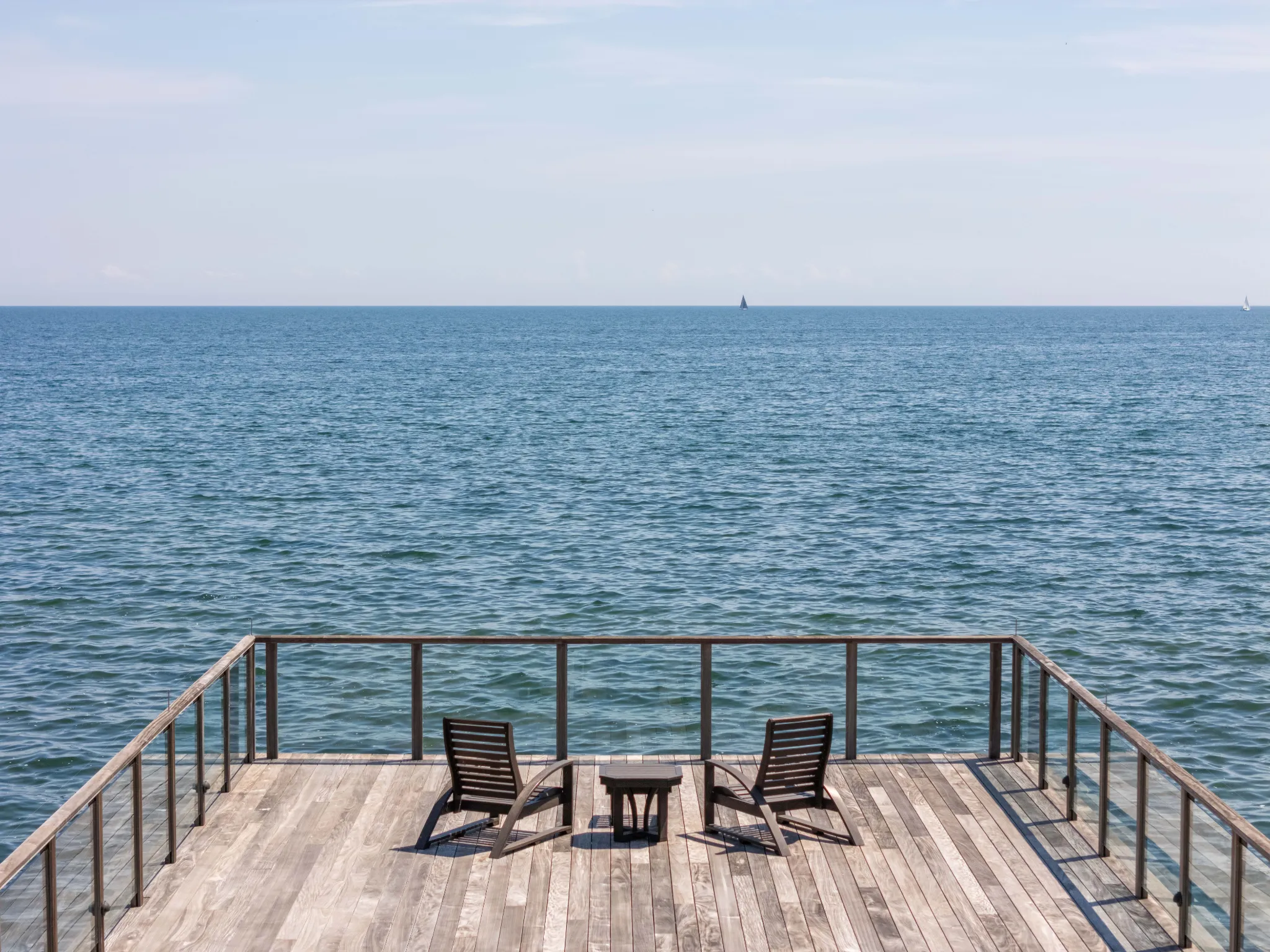 a serene photo of two chairs on the deck, overlooking the lake