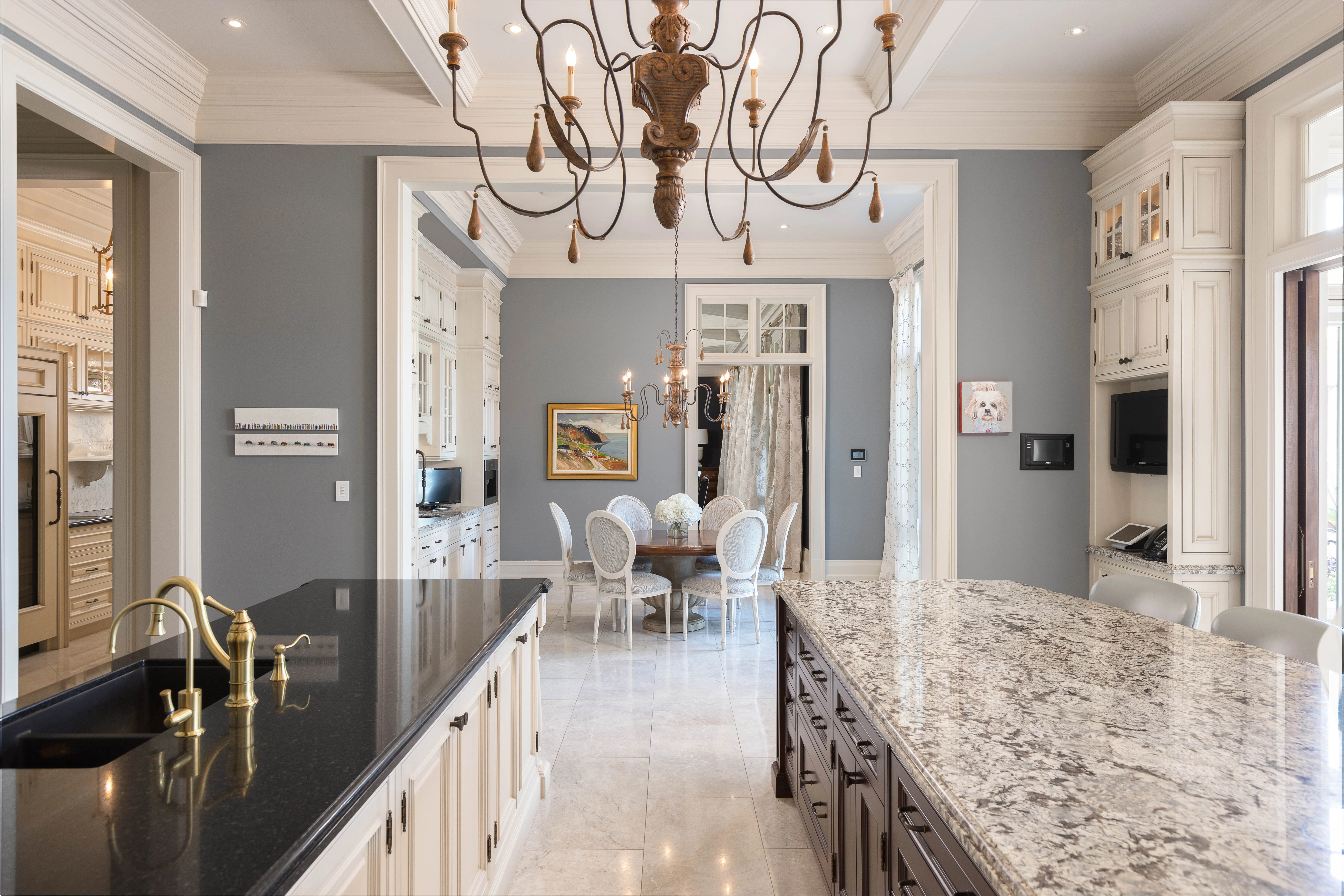 lavish kitchen with two islands and large opulent chandelier overlooking the sun room