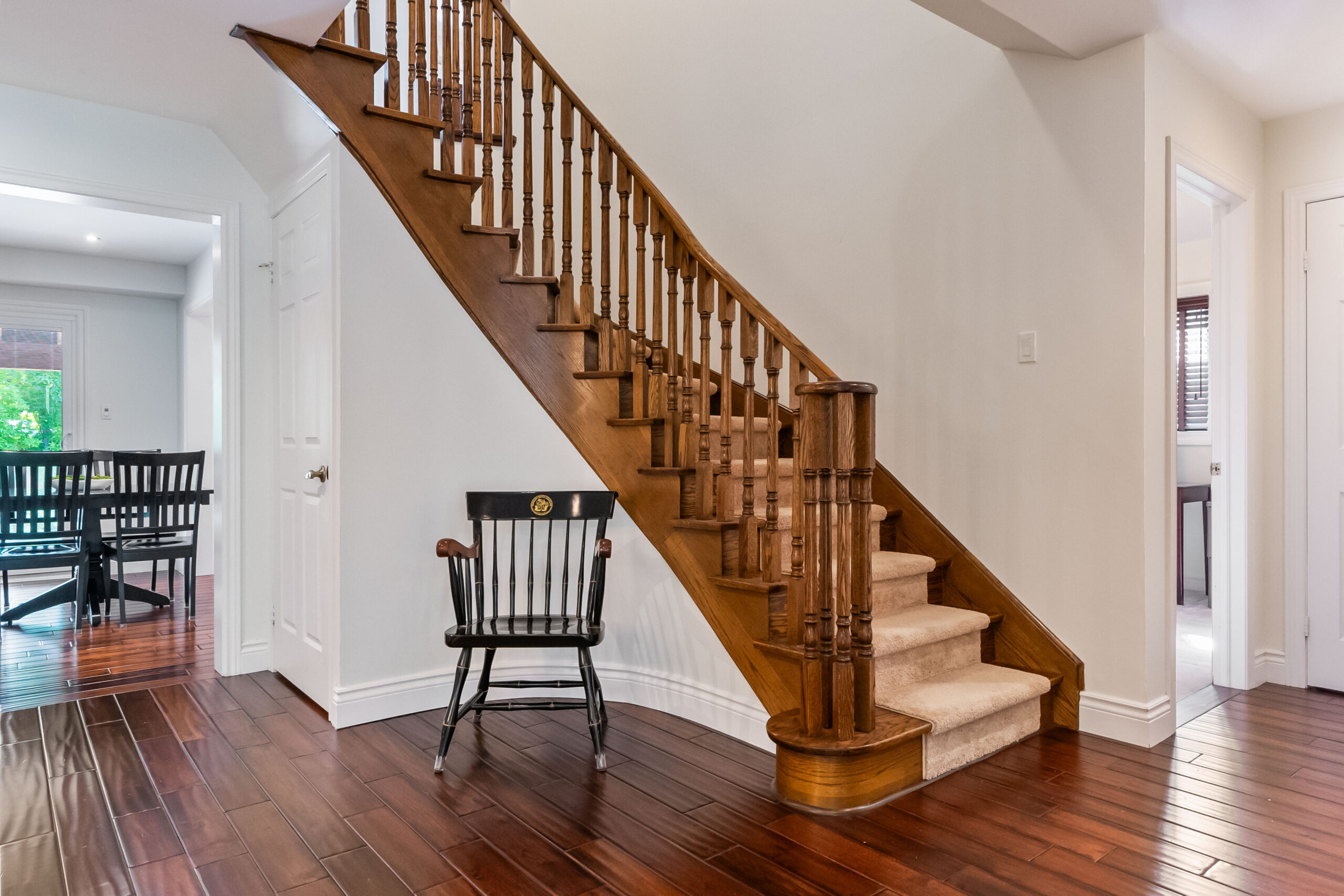 Wooden staircase leading to an upper floor with a black chair nearby