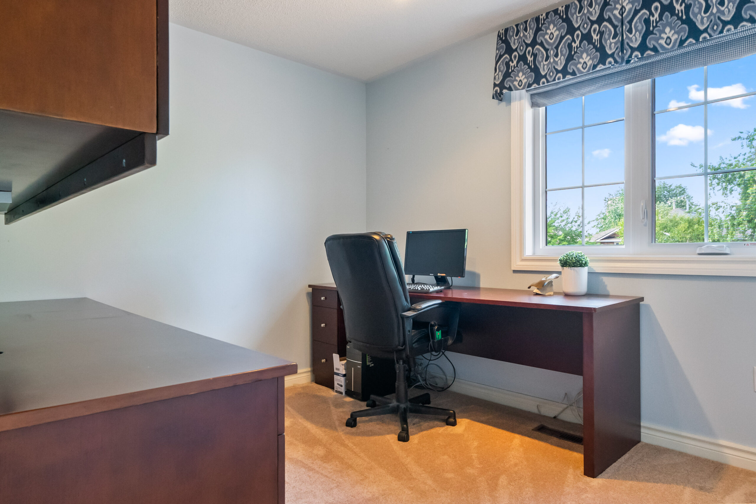 Home office with a wooden desk, computer, and window view