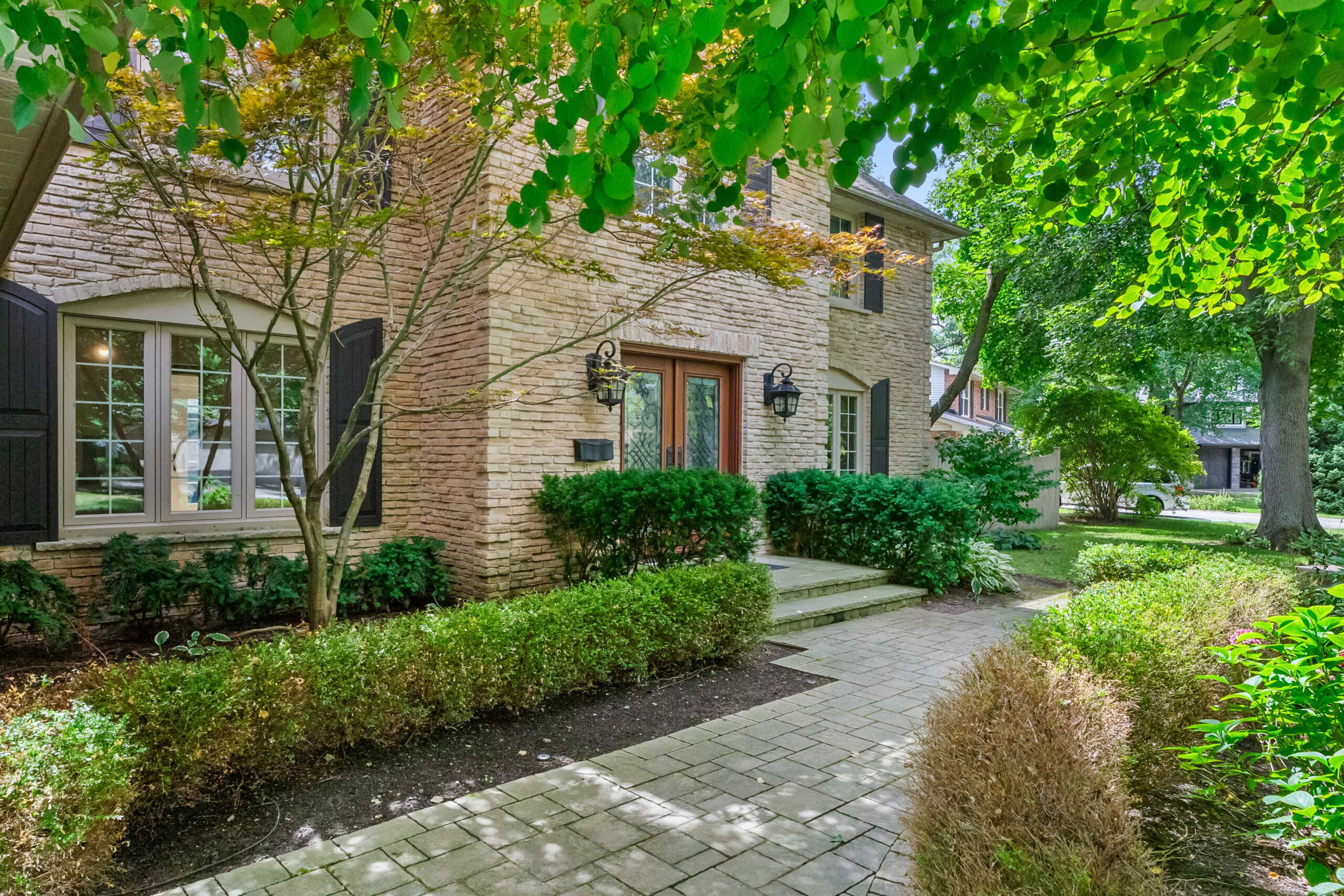 Brick house with landscaped garden and stone pathway under green trees