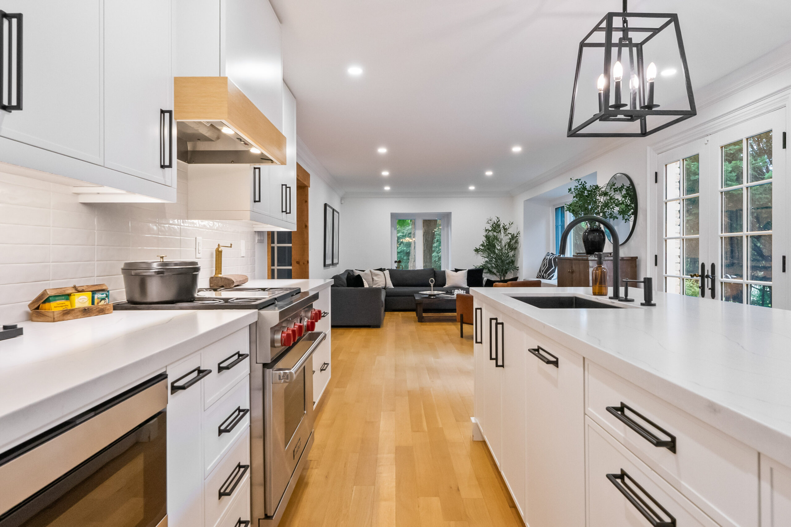 Modern kitchen with white cabinets, stainless steel appliances, and wooden flooring