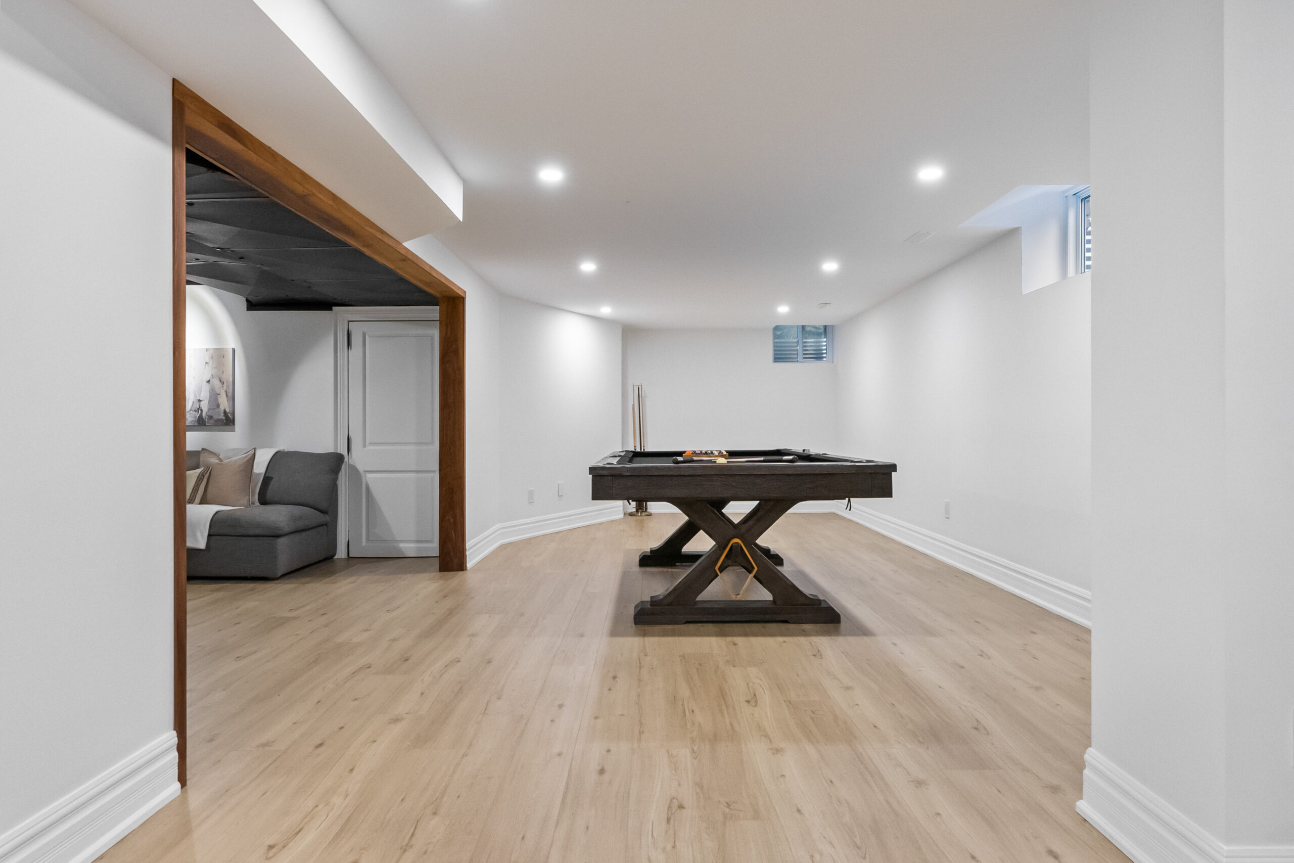 Spacious basement with a pool table and a cozy seating area