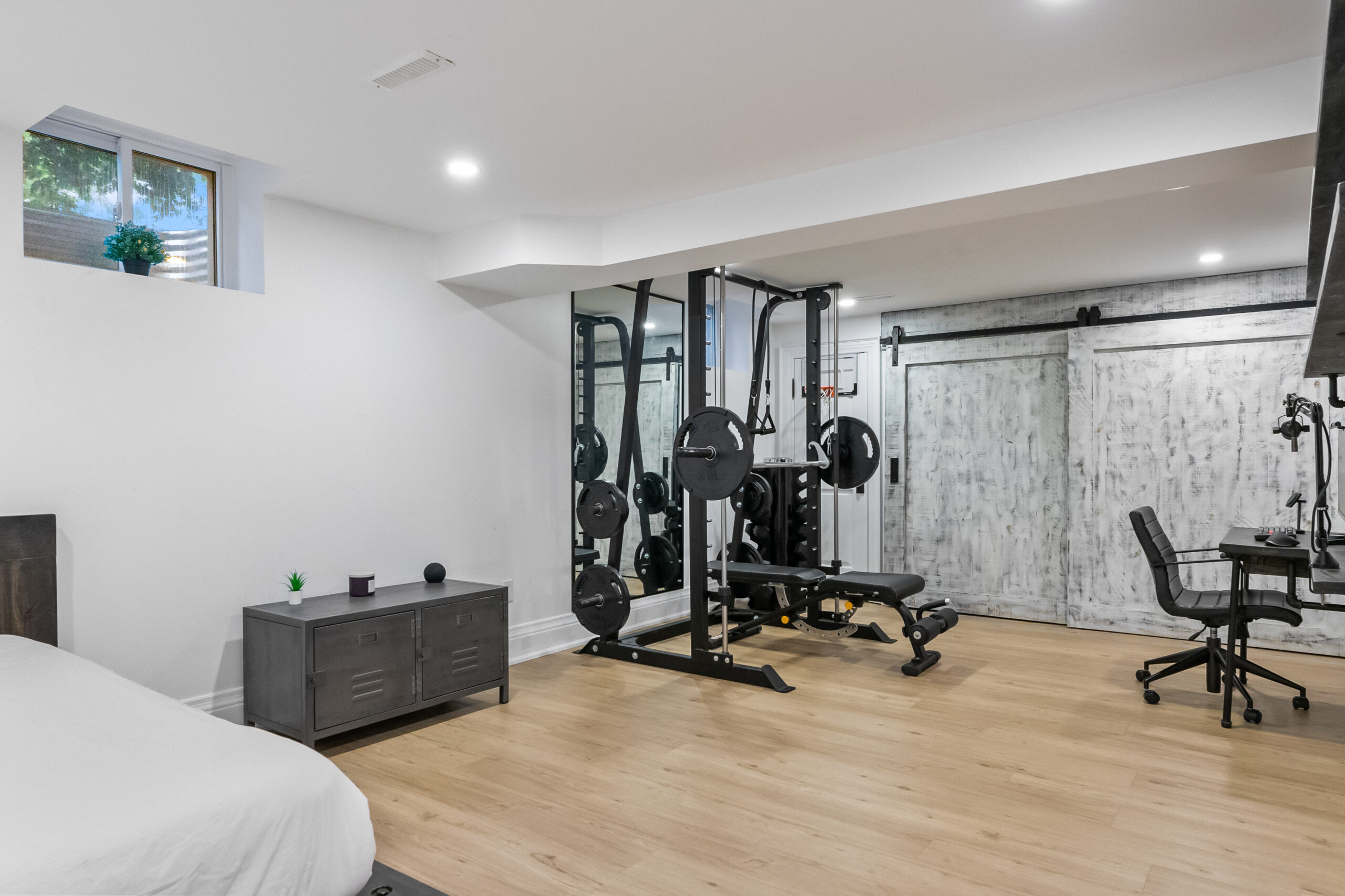 Modern gym and workspace in a bright, spacious room with wooden flooring.