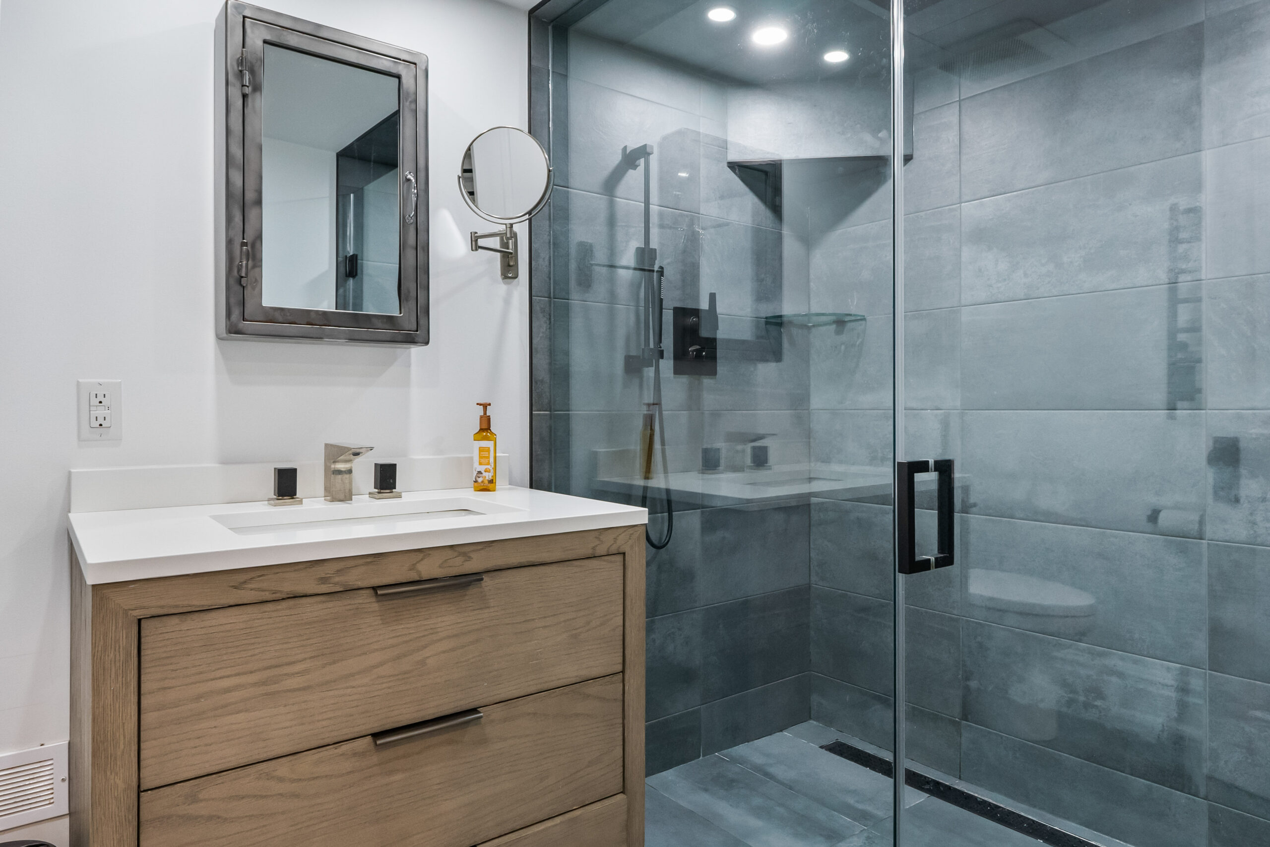 Modern bathroom featuring a glass shower and wooden vanity with a mirror
