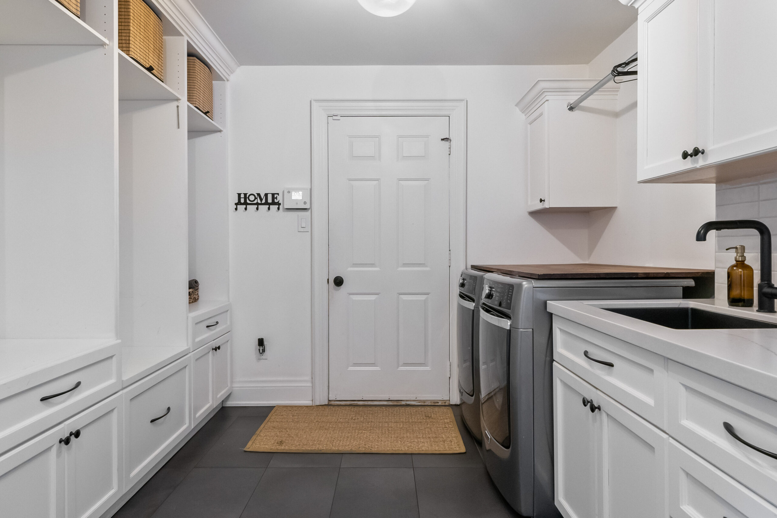 Modern laundry room with white cabinetry and stainless steel appliances