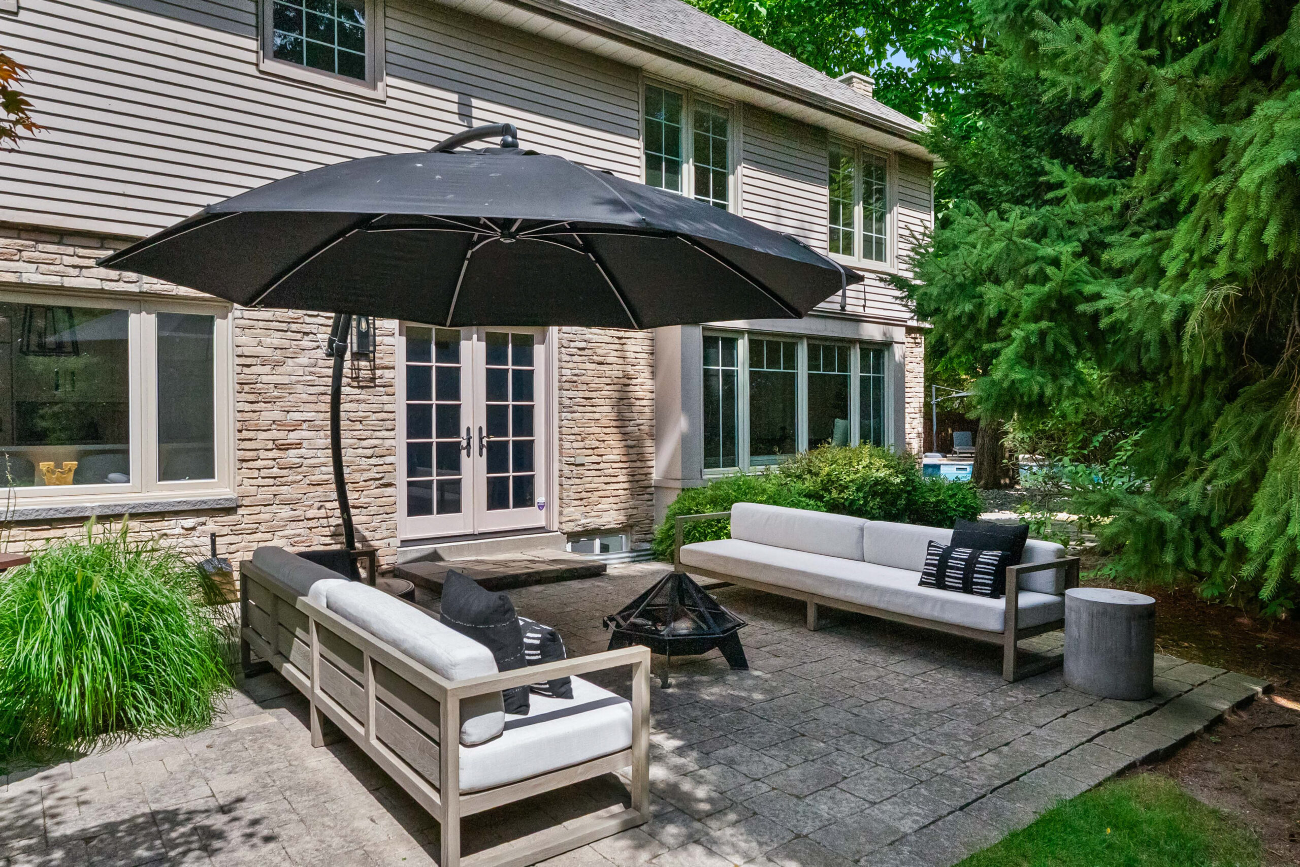 Cozy outdoor seating area with a black umbrella and stone wall backdrop