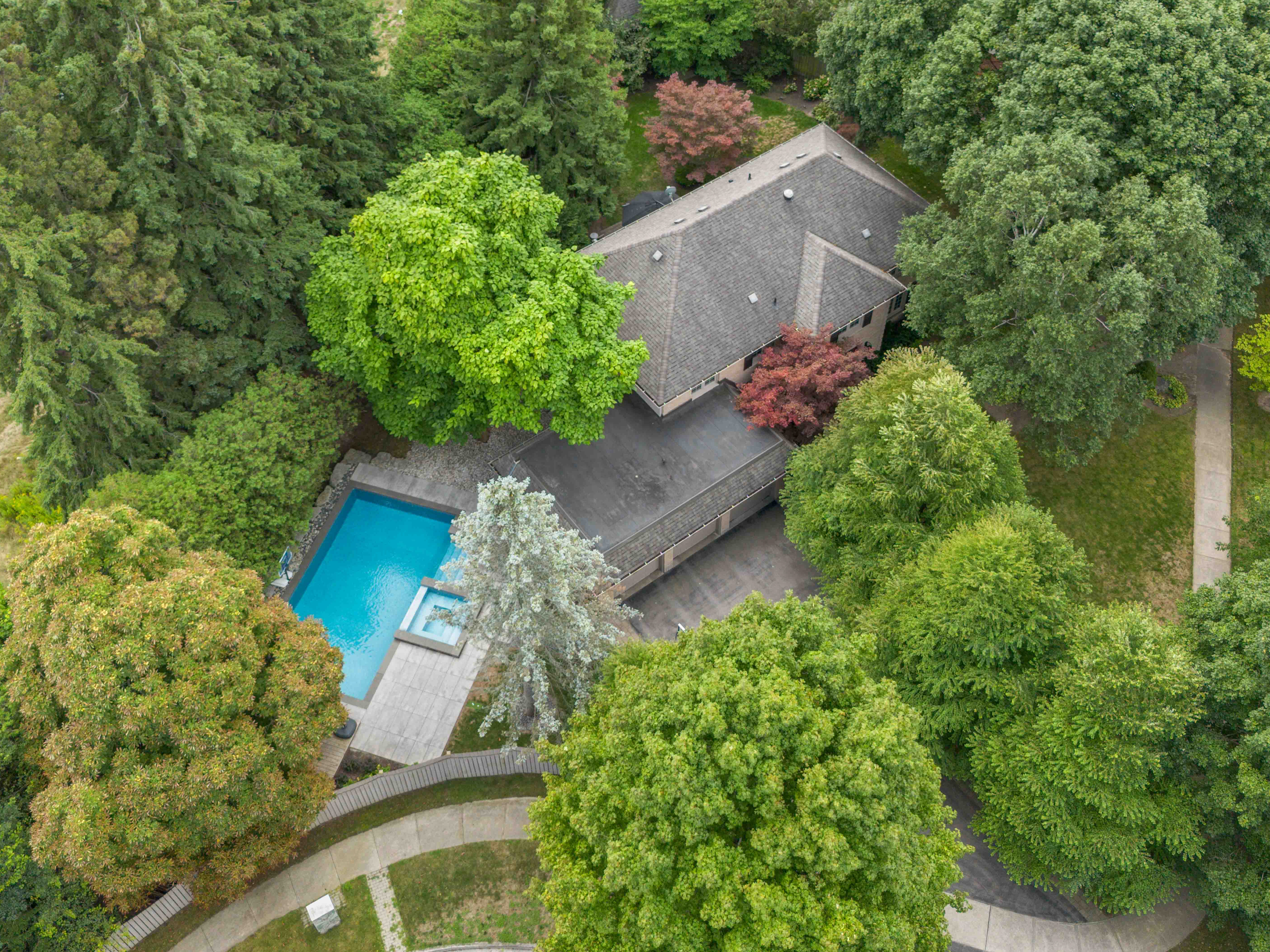 Aerial view of a house surrounded by lush greenery and a swimming pool
