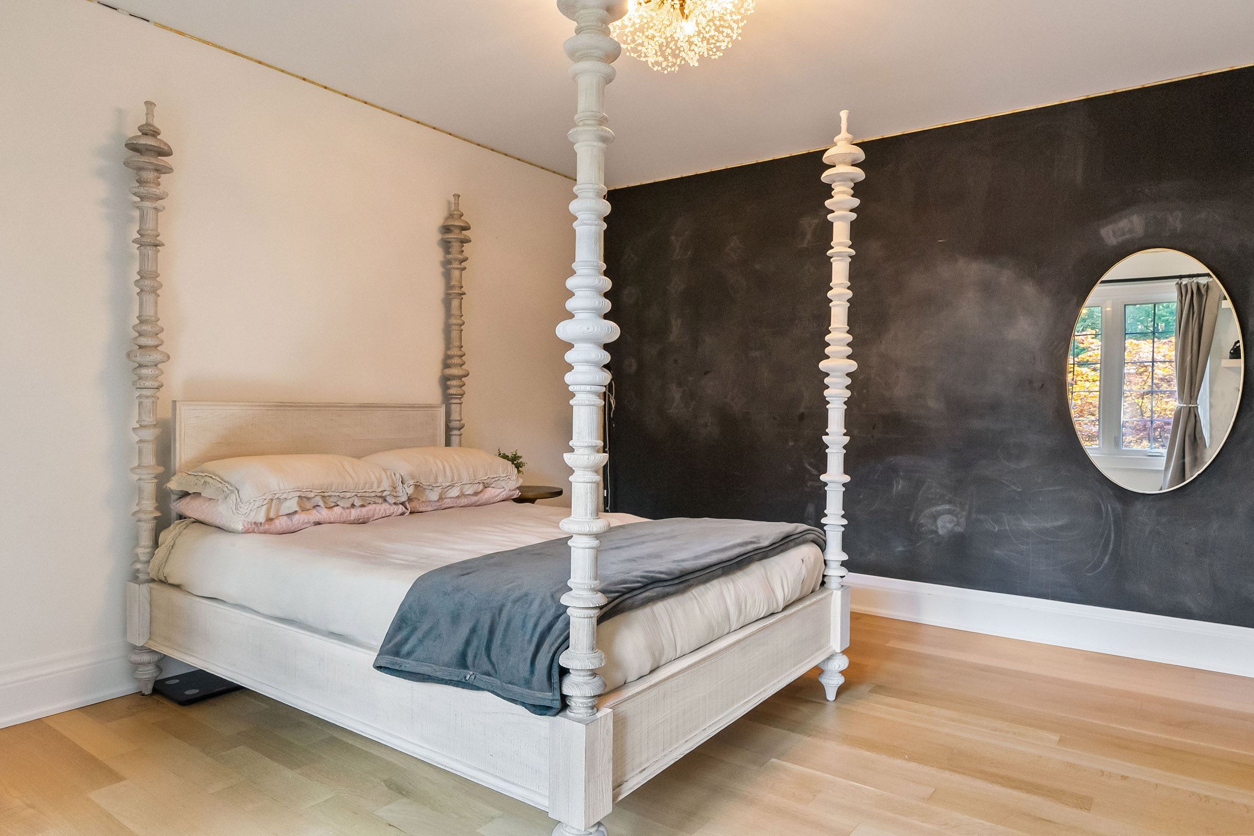Elegant bedroom featuring a four-poster bed and a round mirror on the wall