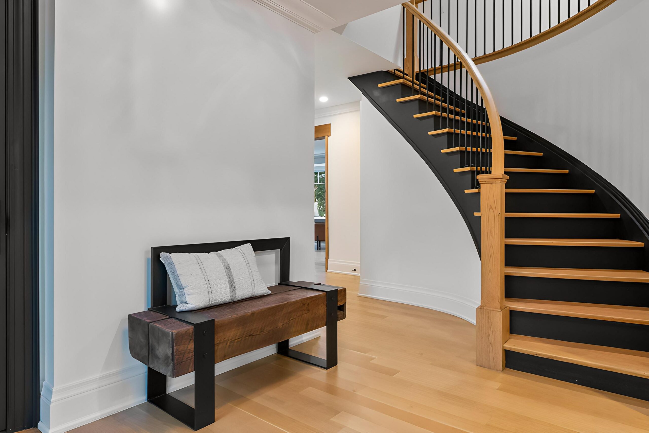 Modern entryway featuring a wooden bench and a curved staircase