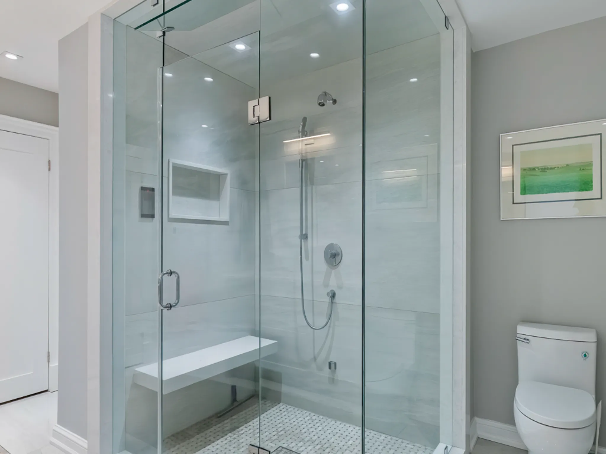 Modern bathroom featuring a glass shower, bench, and toilet