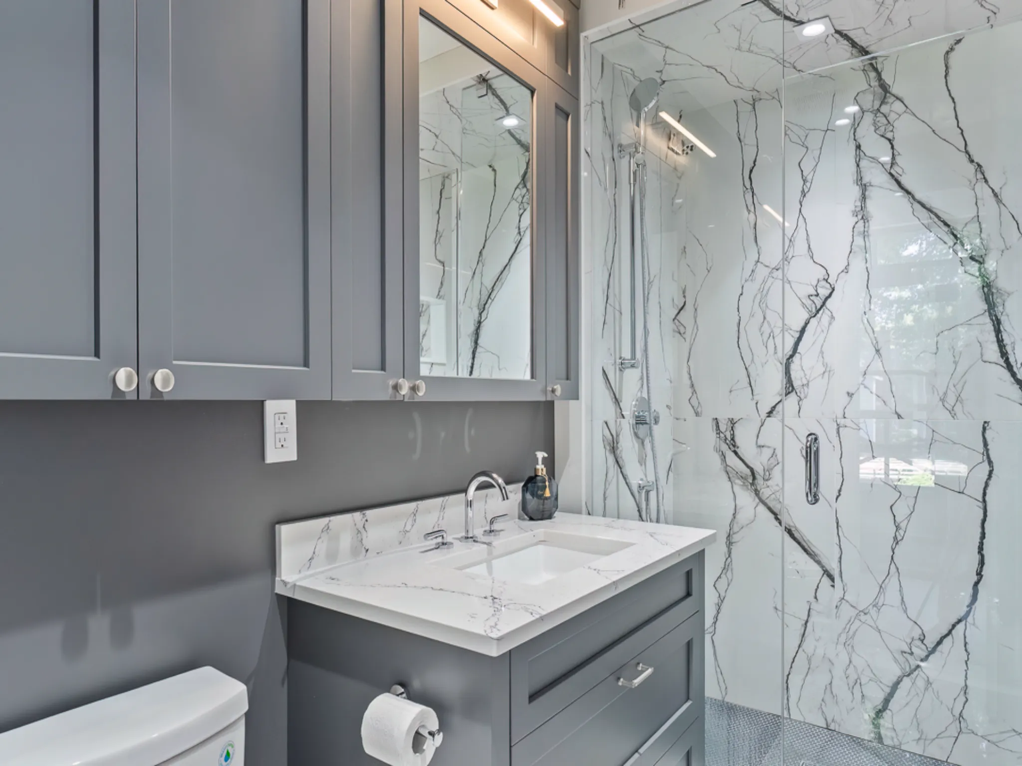 Modern bathroom with gray cabinetry and marble shower walls
