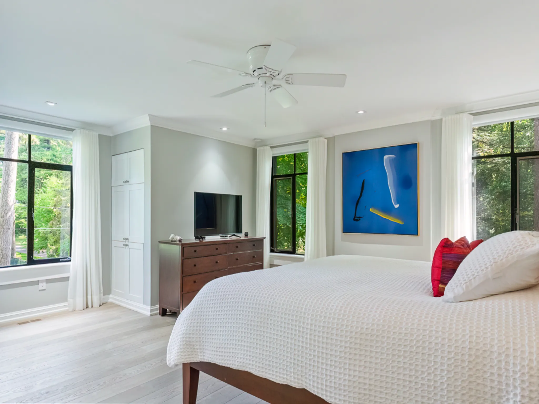 Bright bedroom with large windows, modern decor, and abstract wall art