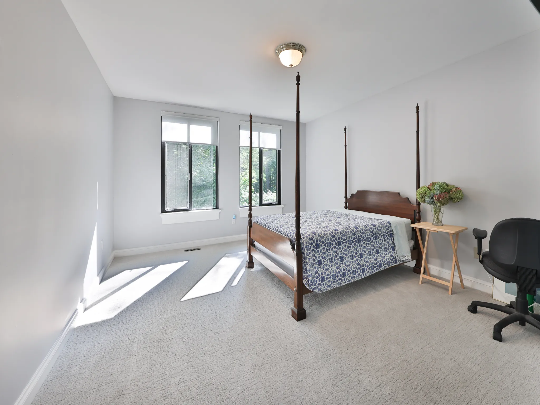 Bright bedroom featuring a four-poster bed and large windows