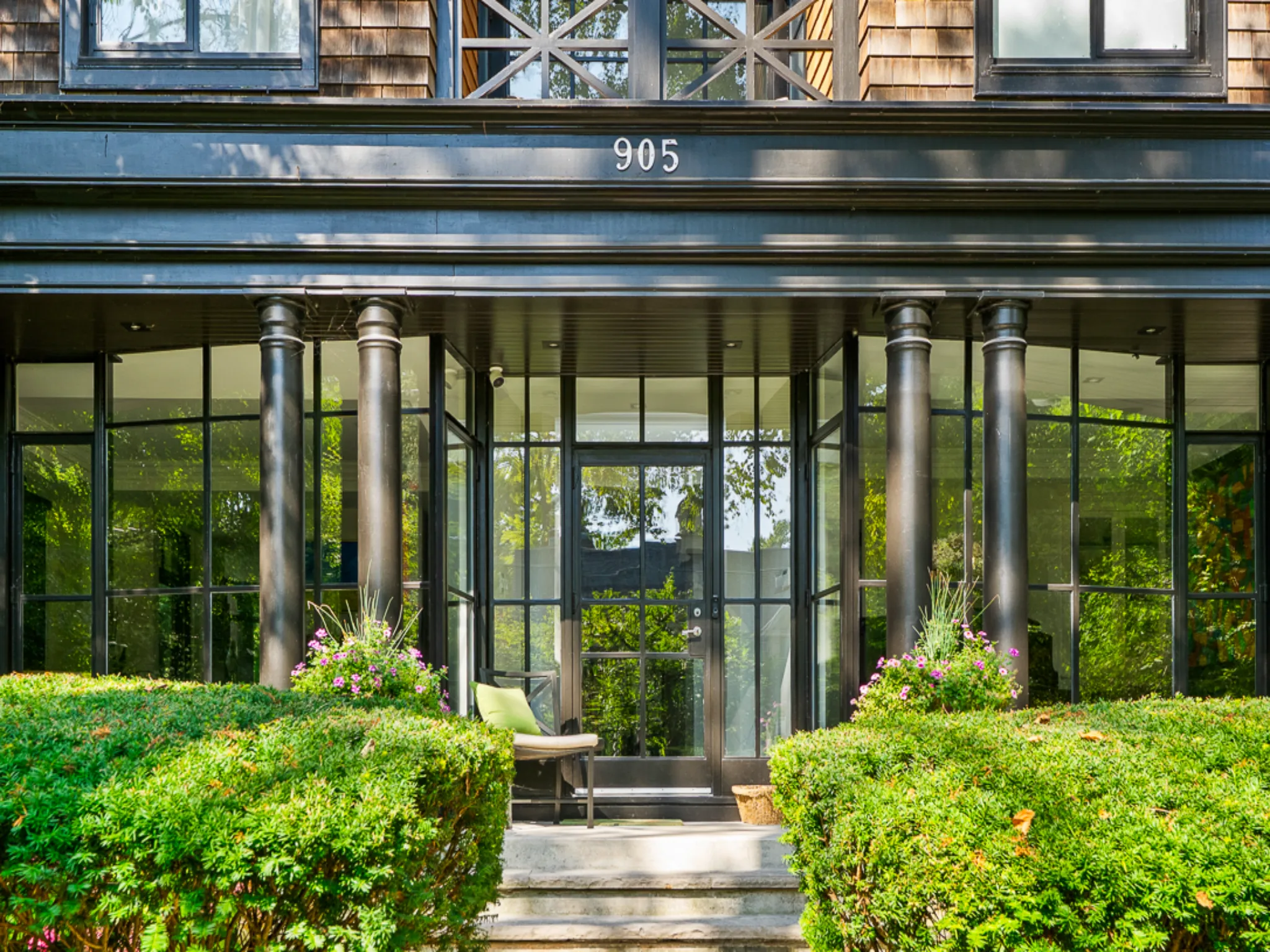 Modern entrance with glass walls and lush greenery