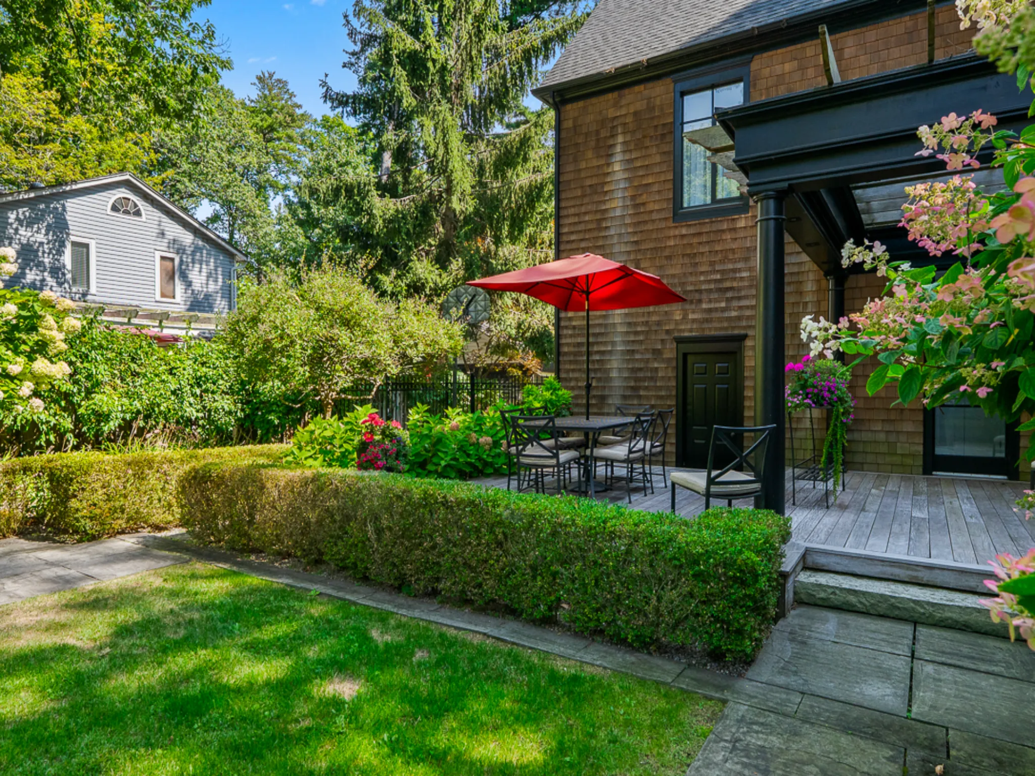 Cozy backyard patio with red umbrella and lush greenery