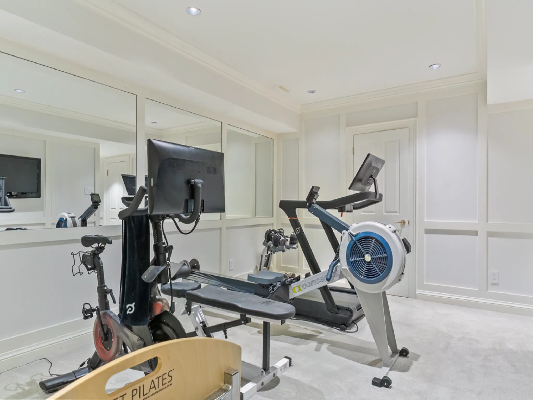 Home gym featuring a rowing machine and stationary bike with mirrors