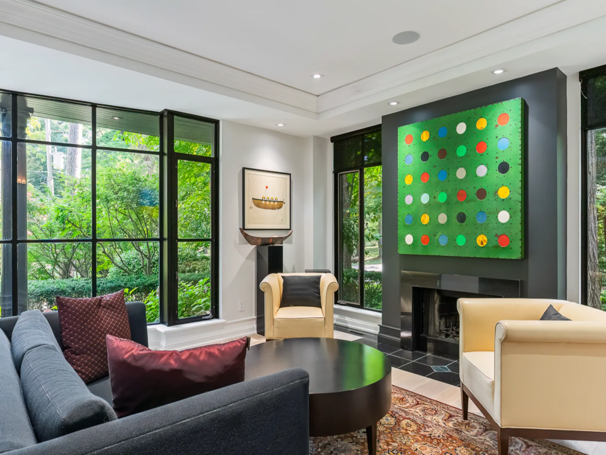 Modern living room with large windows, colorful artwork, and stylish furniture