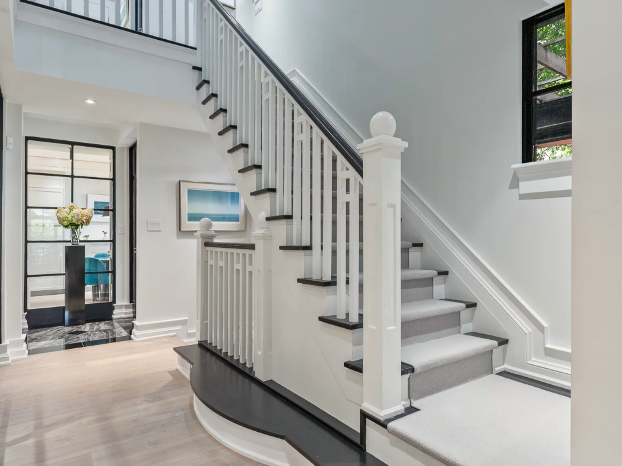 Modern staircase with white railings and dark steps, bright hallway setting