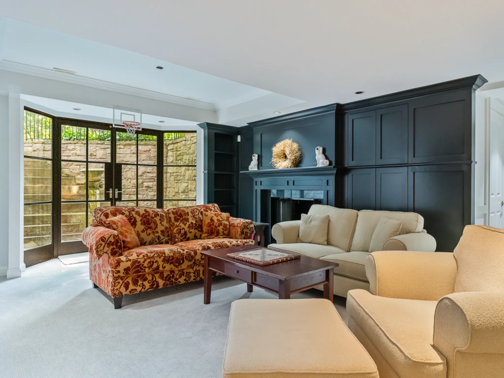Cozy living room with patterned sofa, beige chairs, and large windows