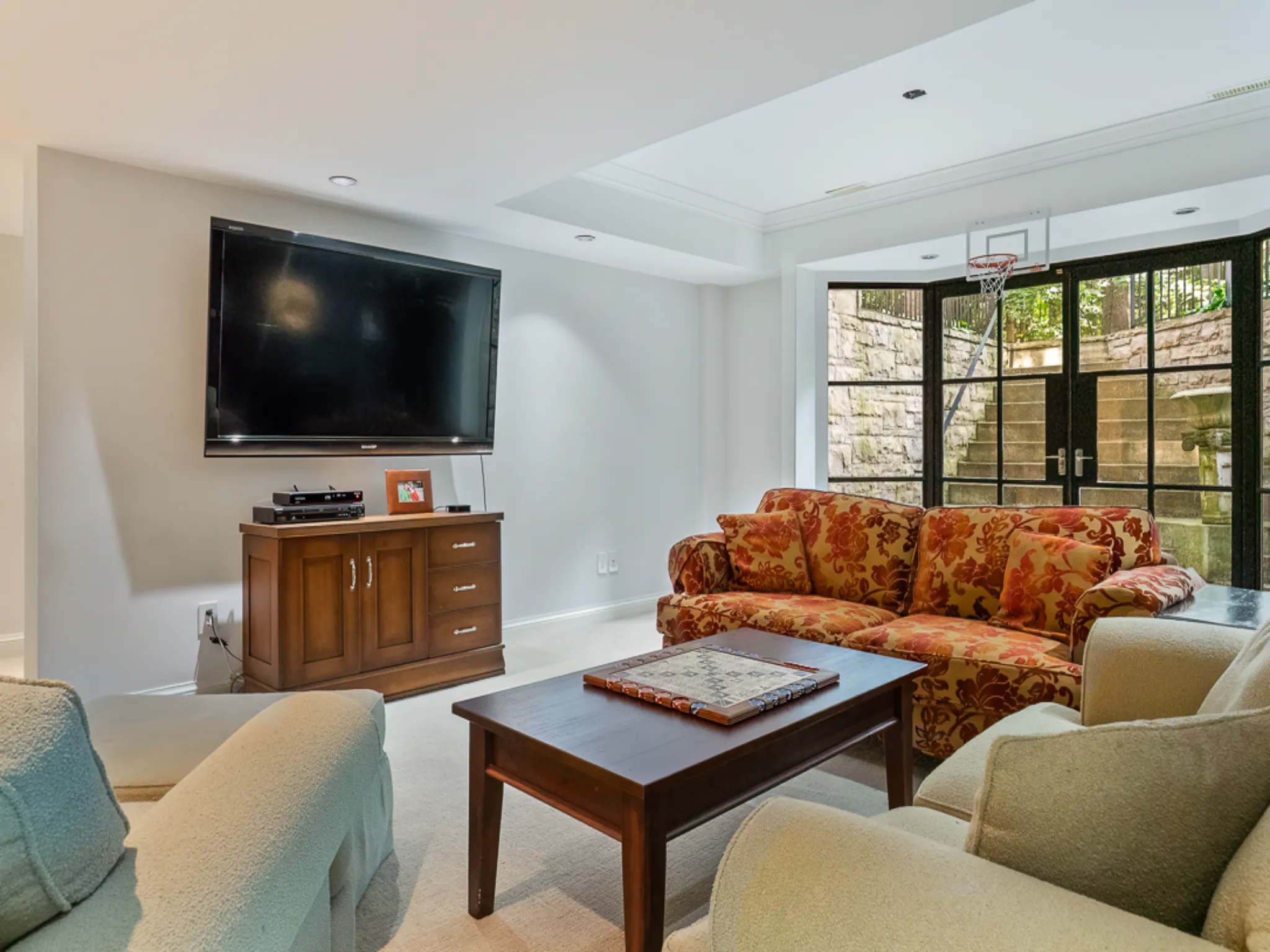 Cozy living room with a large TV, colorful sofa, and wooden coffee table