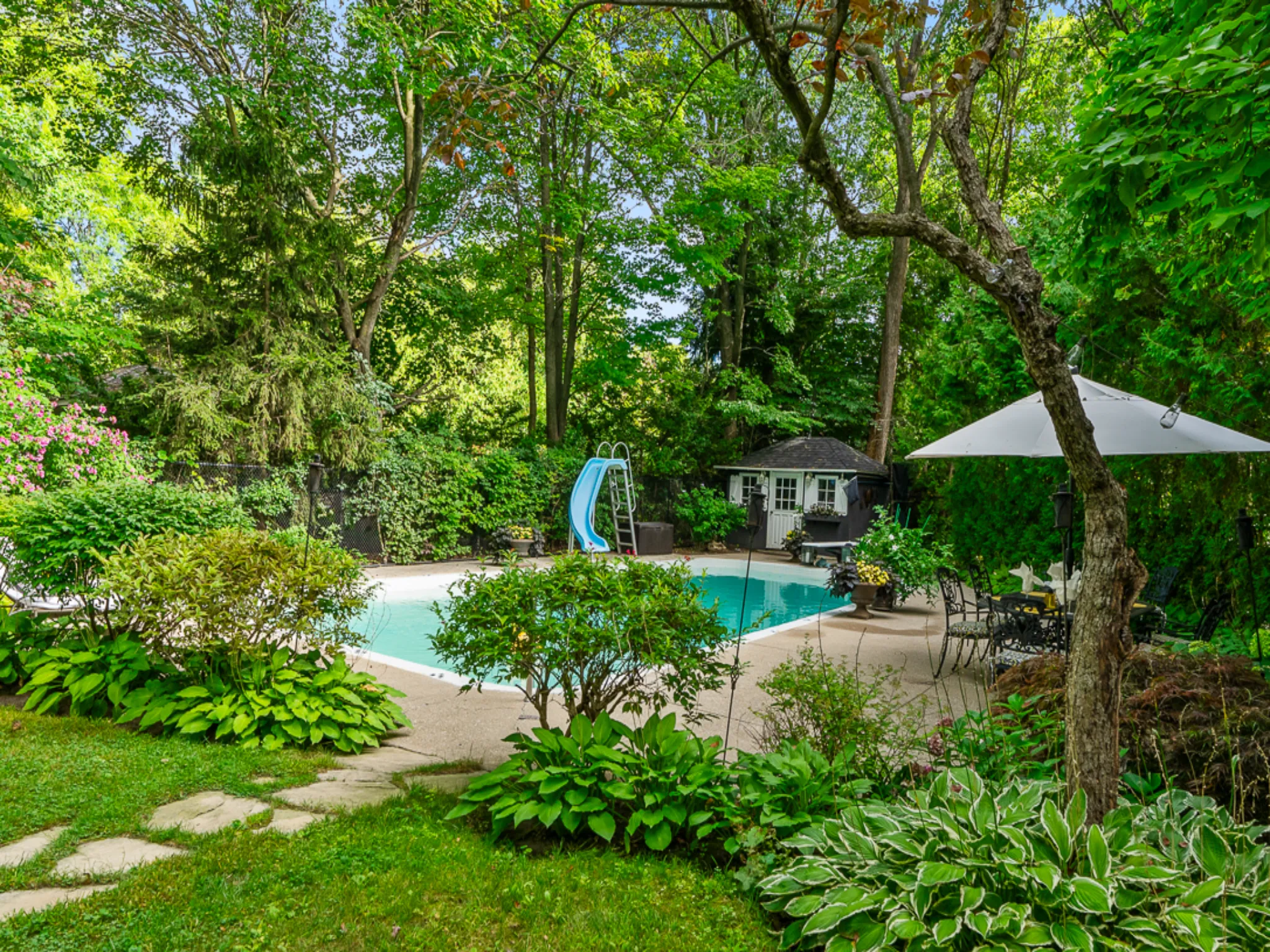 yard with mature plantings and pool with slide