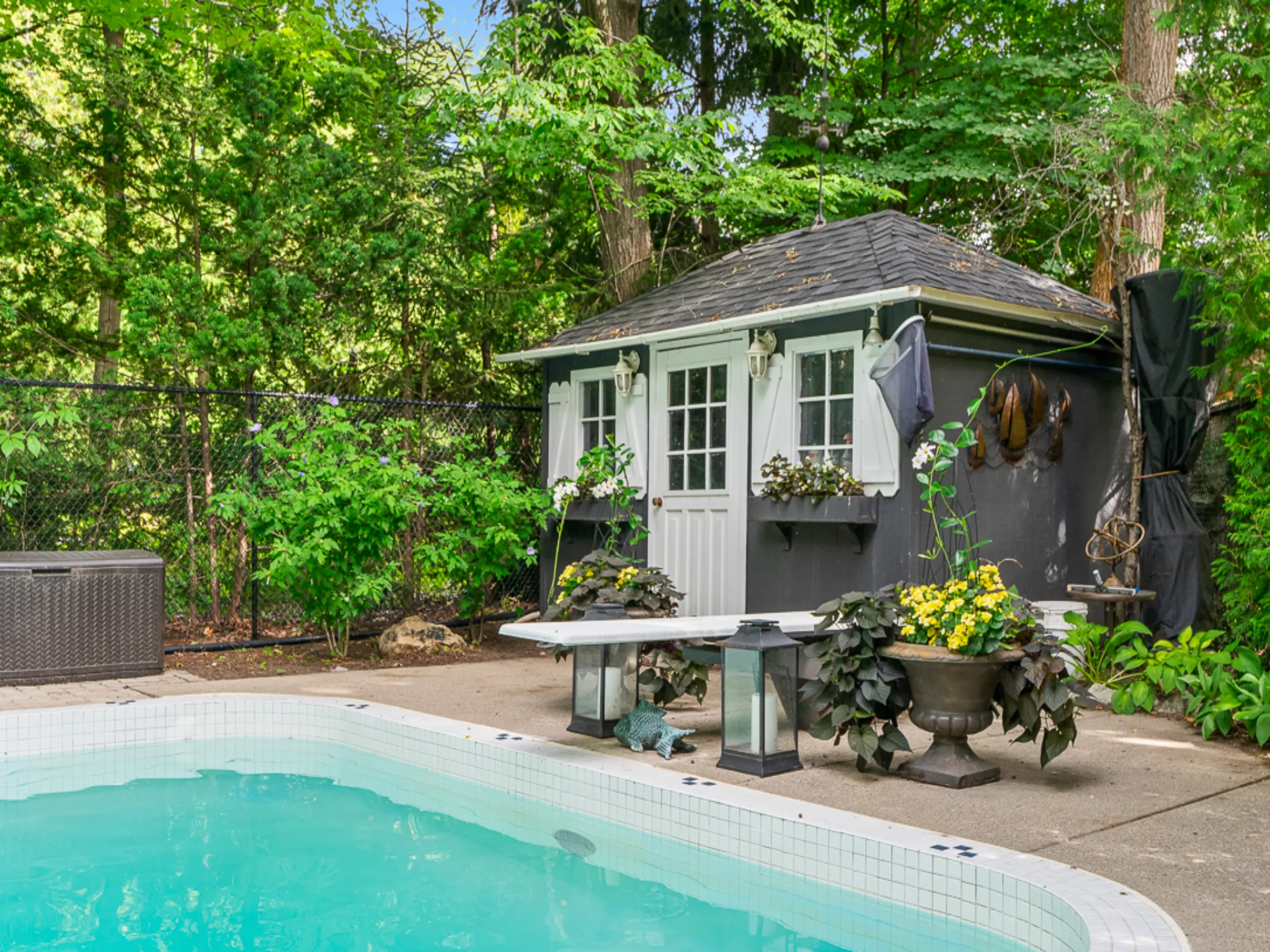 pool side cabana with diving board and lush landscaping