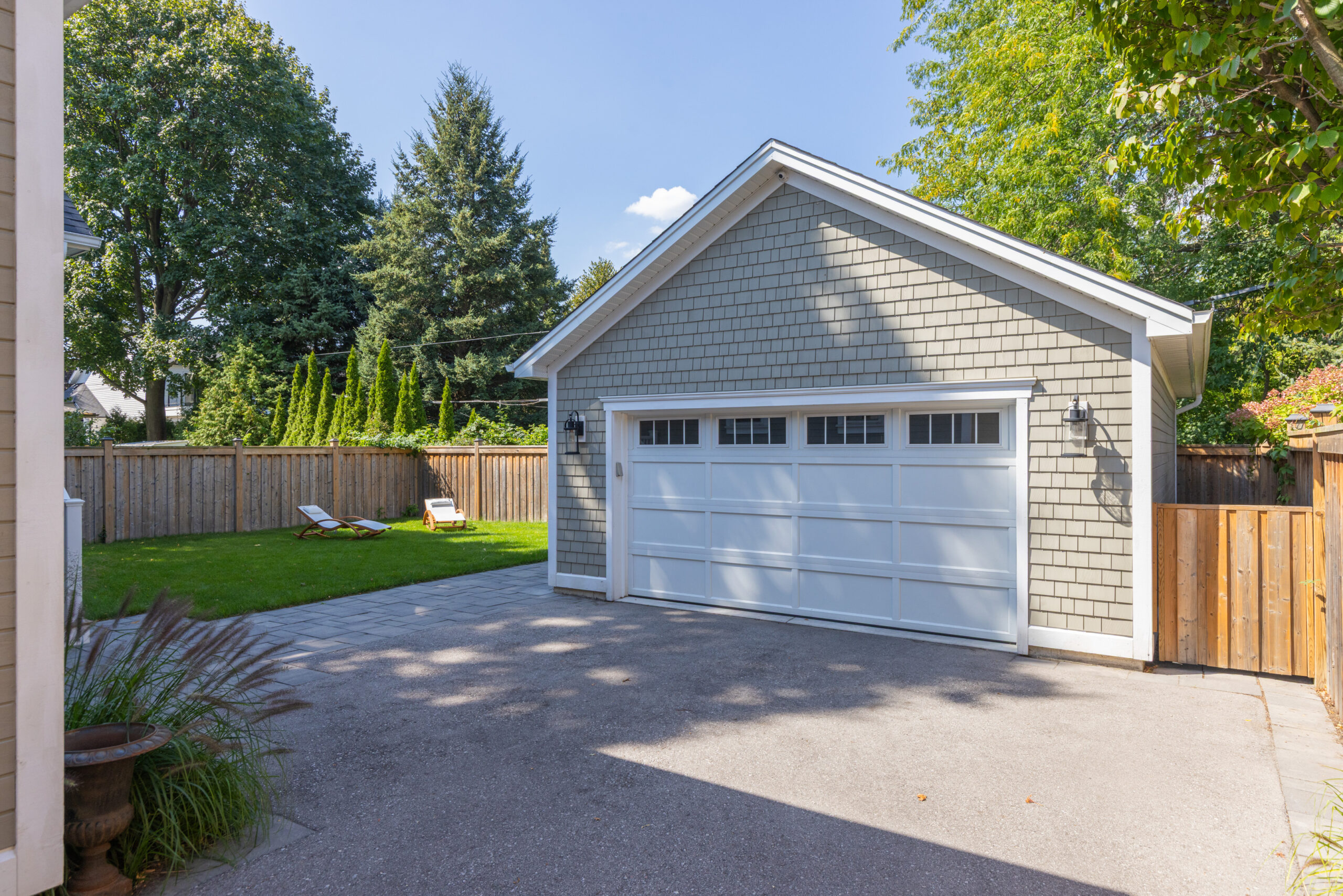 Detached garage with a paved driveway and green lawn in the background