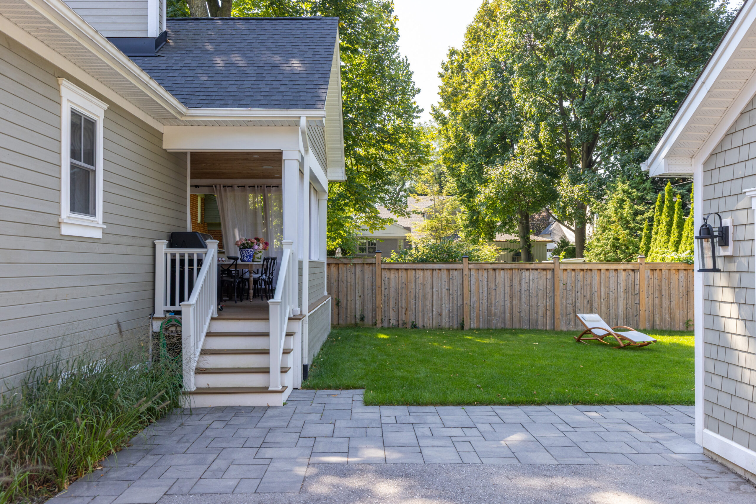 Backyard view featuring a patio, lawn, and lounge chair near a house
