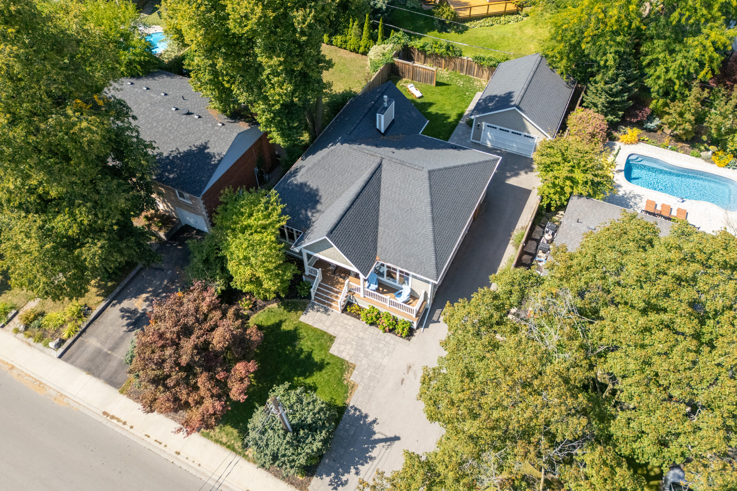 Aerial view of a house with a pool surrounded by trees and landscaping
