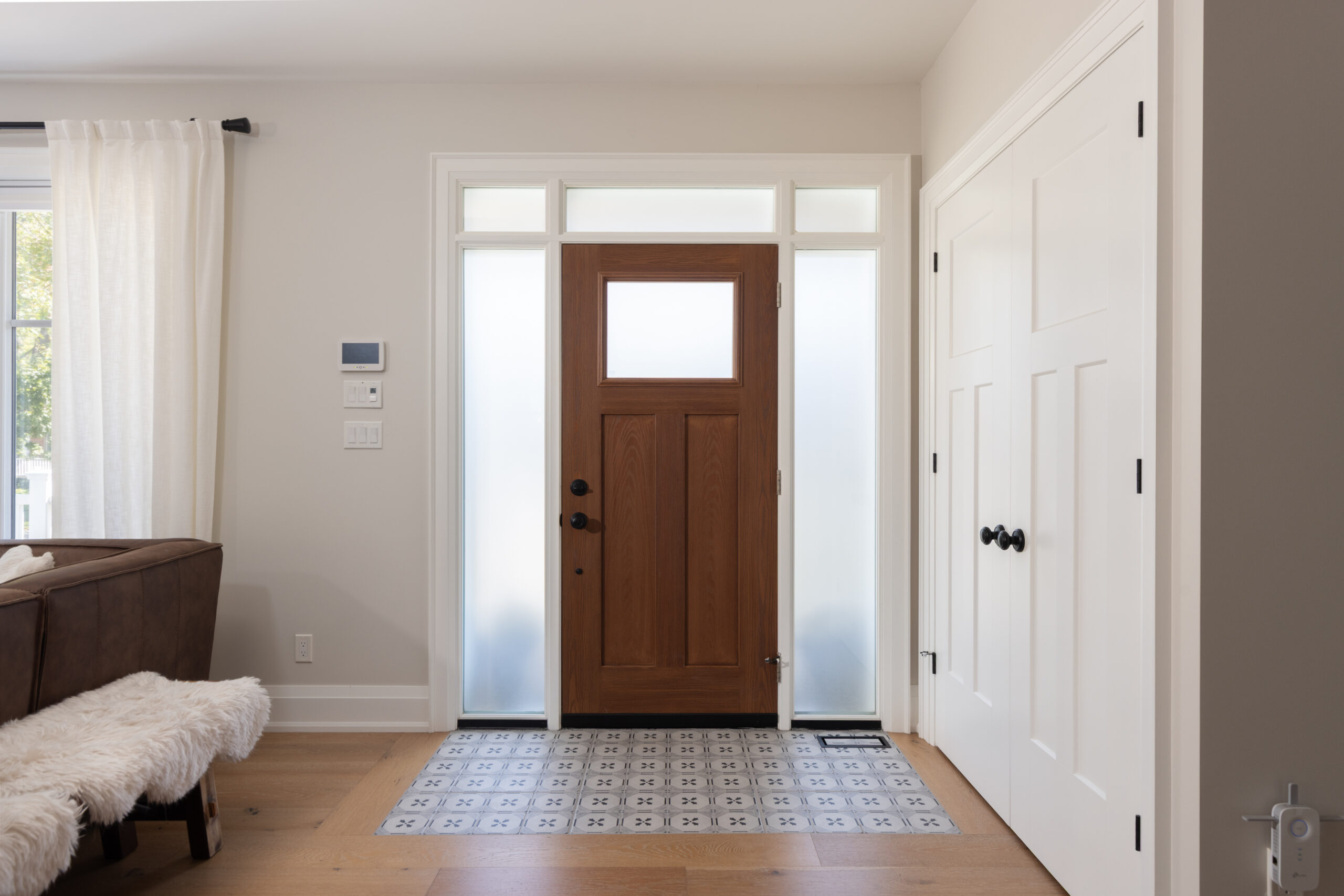 Bright entryway featuring a wooden front door and patterned tile floor