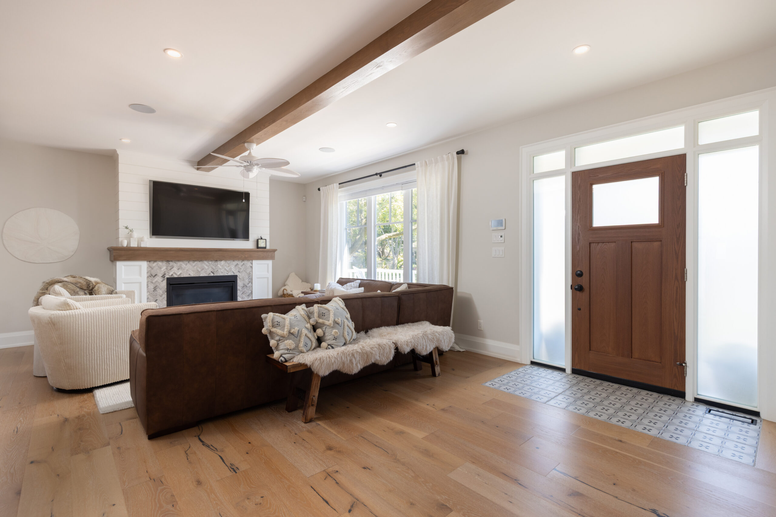 Modern living room with a brown sofa, fireplace, and front door.