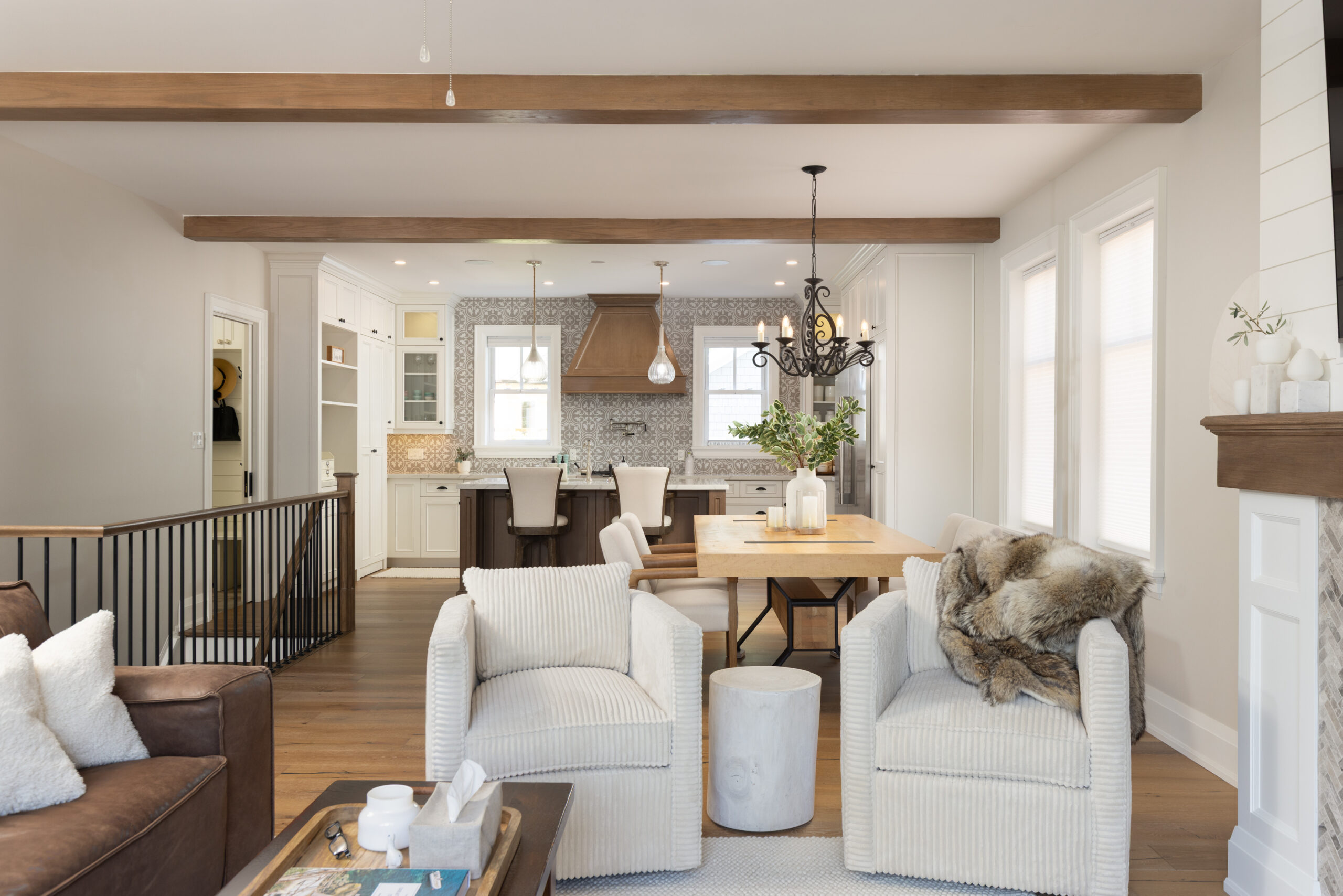 Bright living room with white chairs, wooden beams, and a dining area.