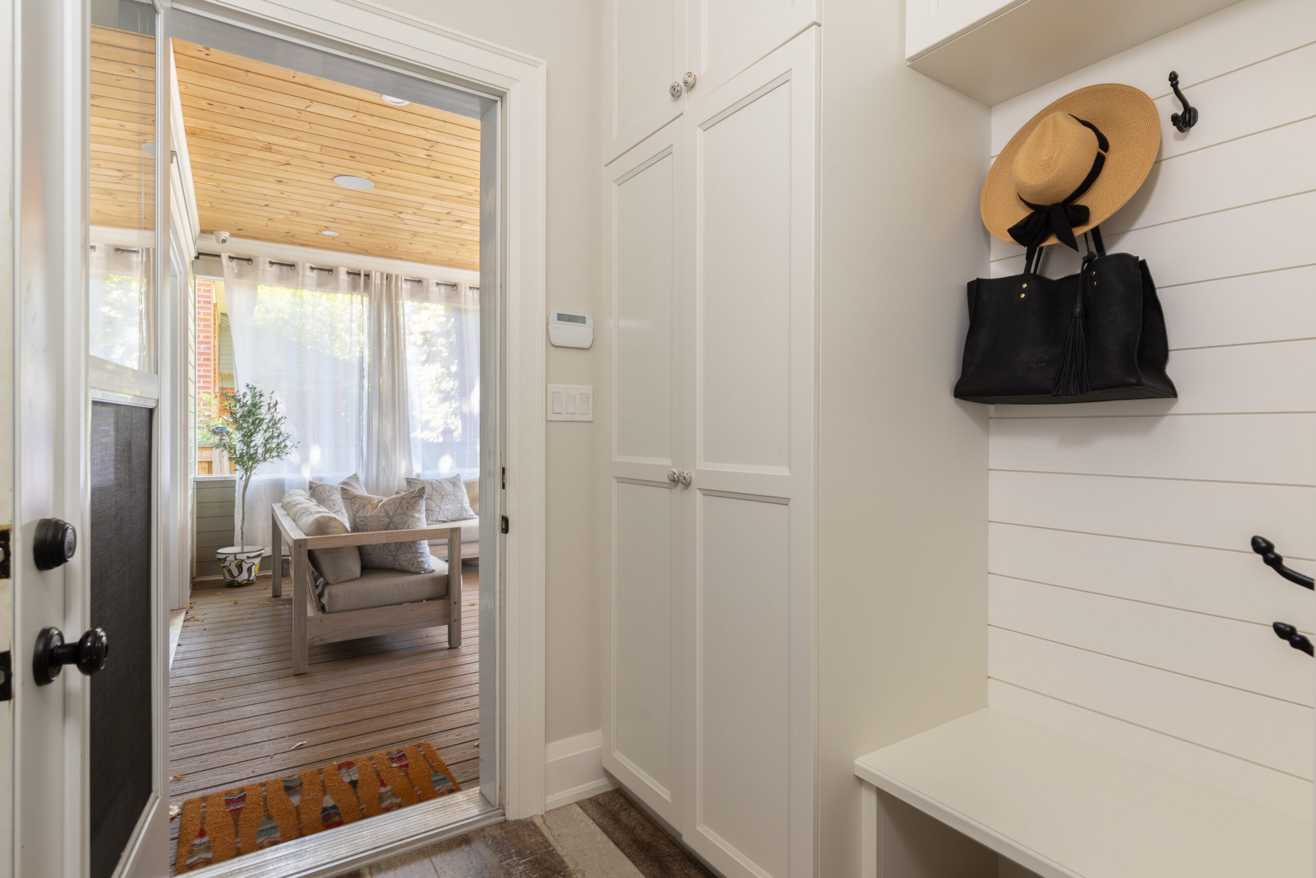 Bright entryway with a hat, bag, and view of a cozy living space