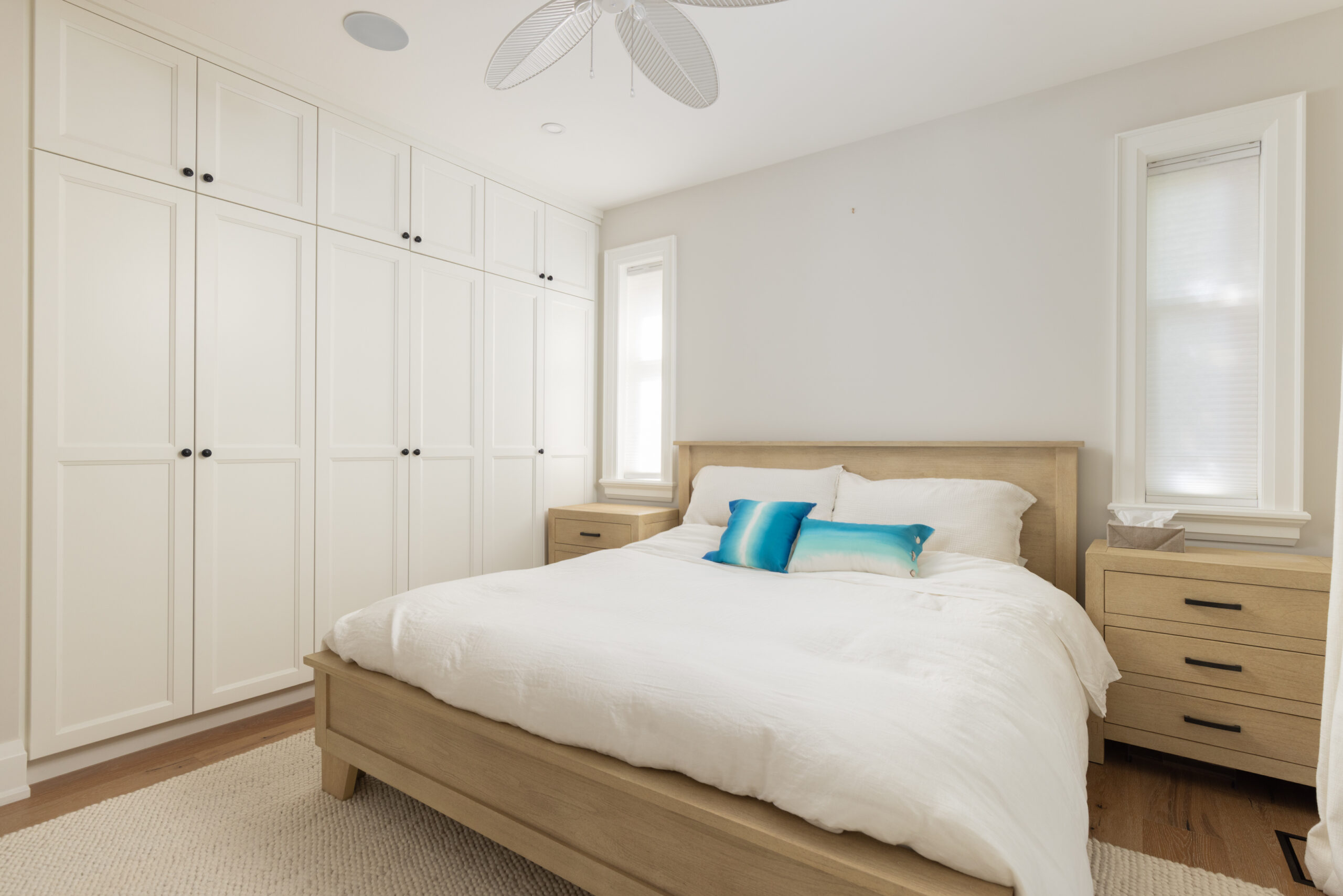 Bright bedroom with a light wood bed and blue accent pillows