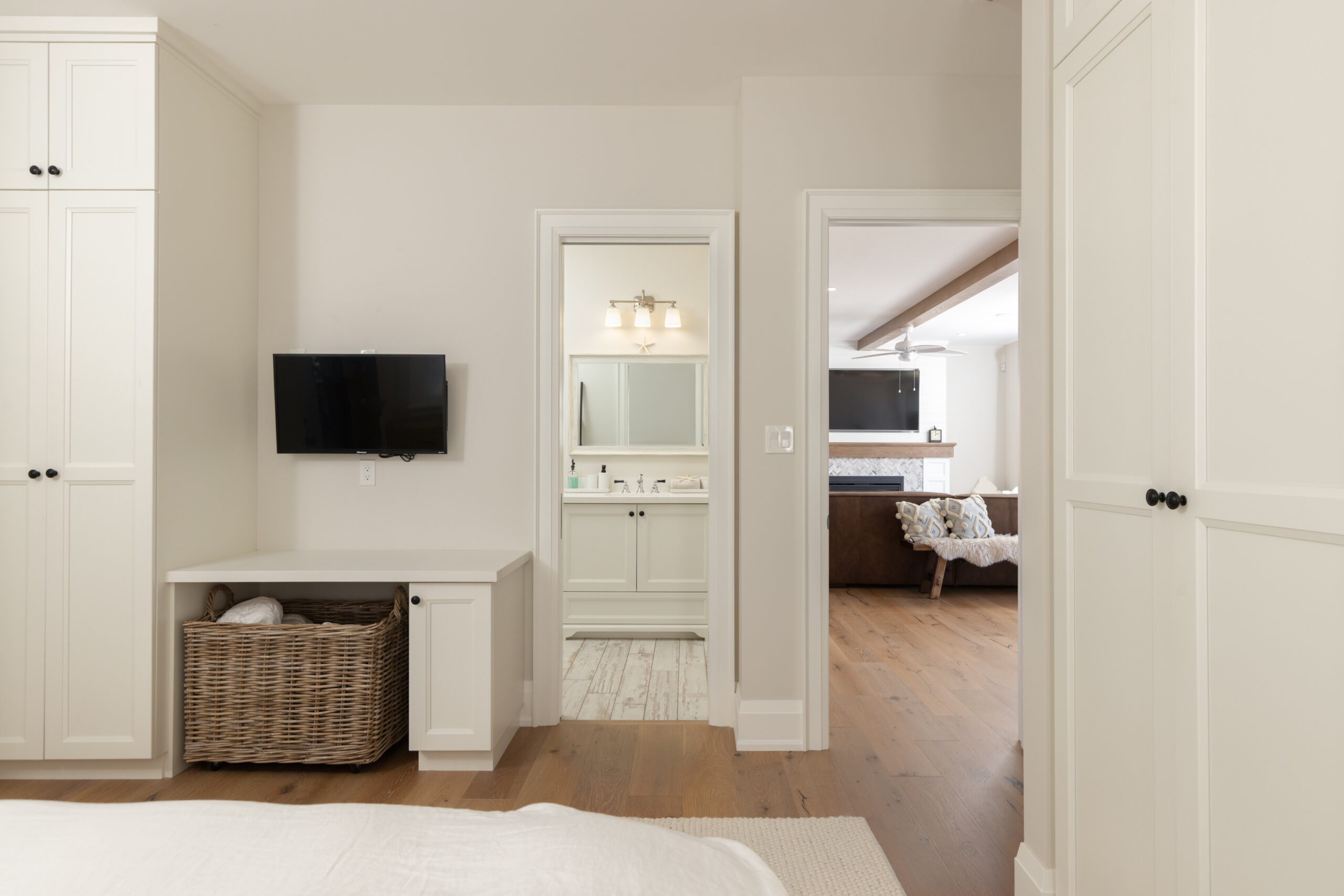 Modern bedroom with a TV, light walls, and a view of the living area.