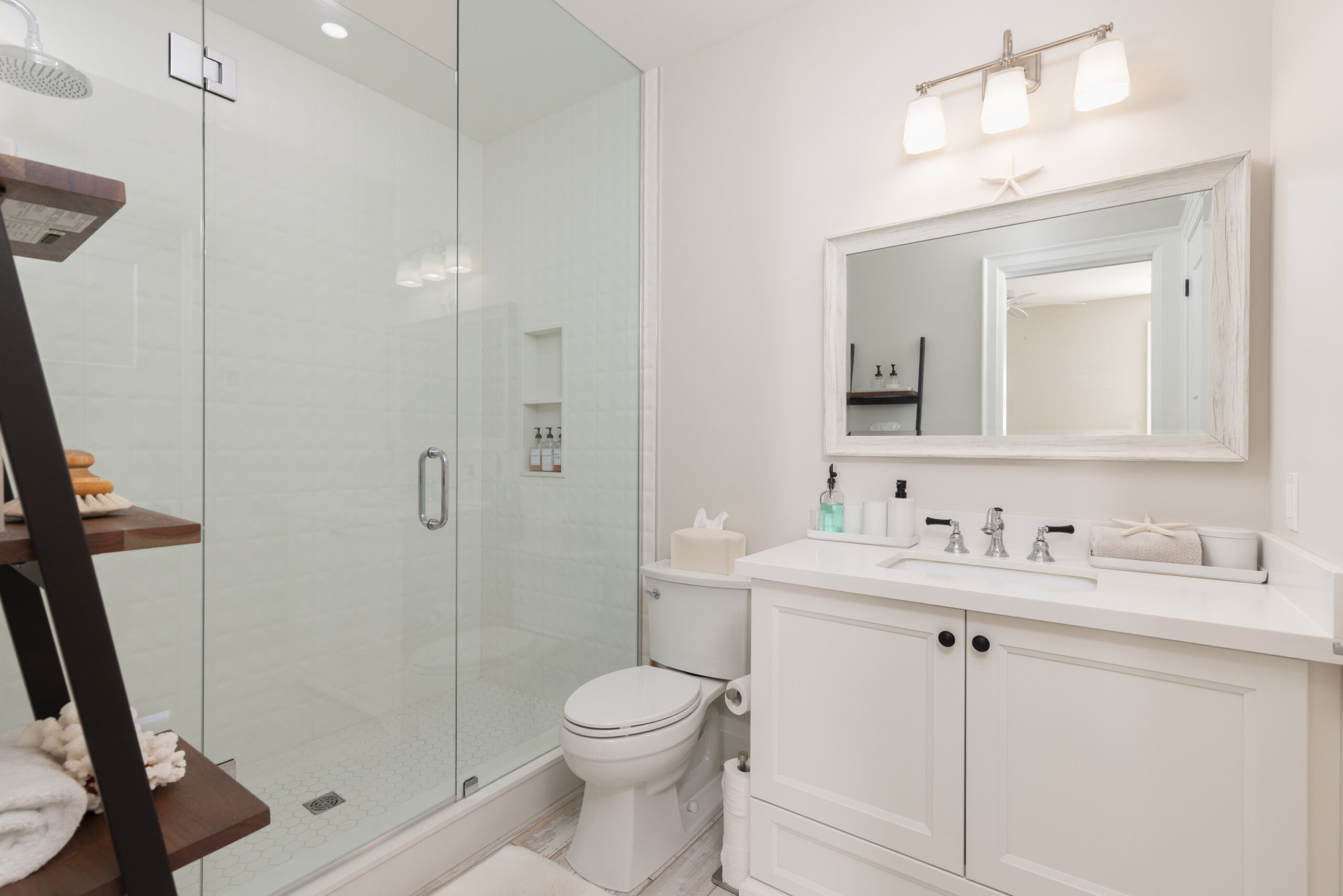Modern bathroom with glass shower, white vanity, and wooden shelf